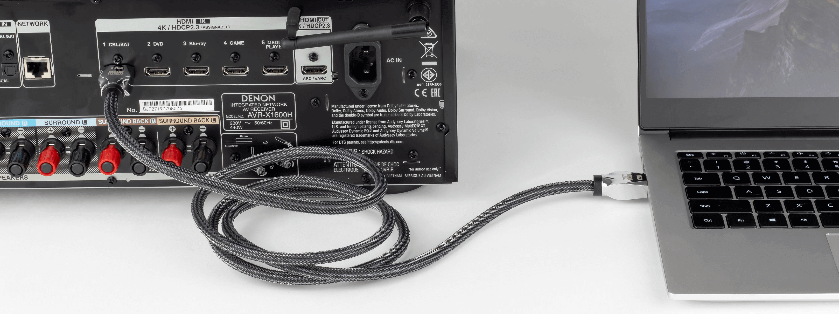 Odbiornik A/V podłączony do laptopa kablem. Białe tło.