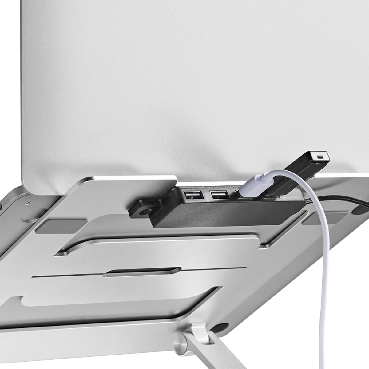 Laptop auf einem silbernen Ständer mit USB-Hub. Kabel und Anschlüsse sind sichtbar. Schlichtes, modernes Design.