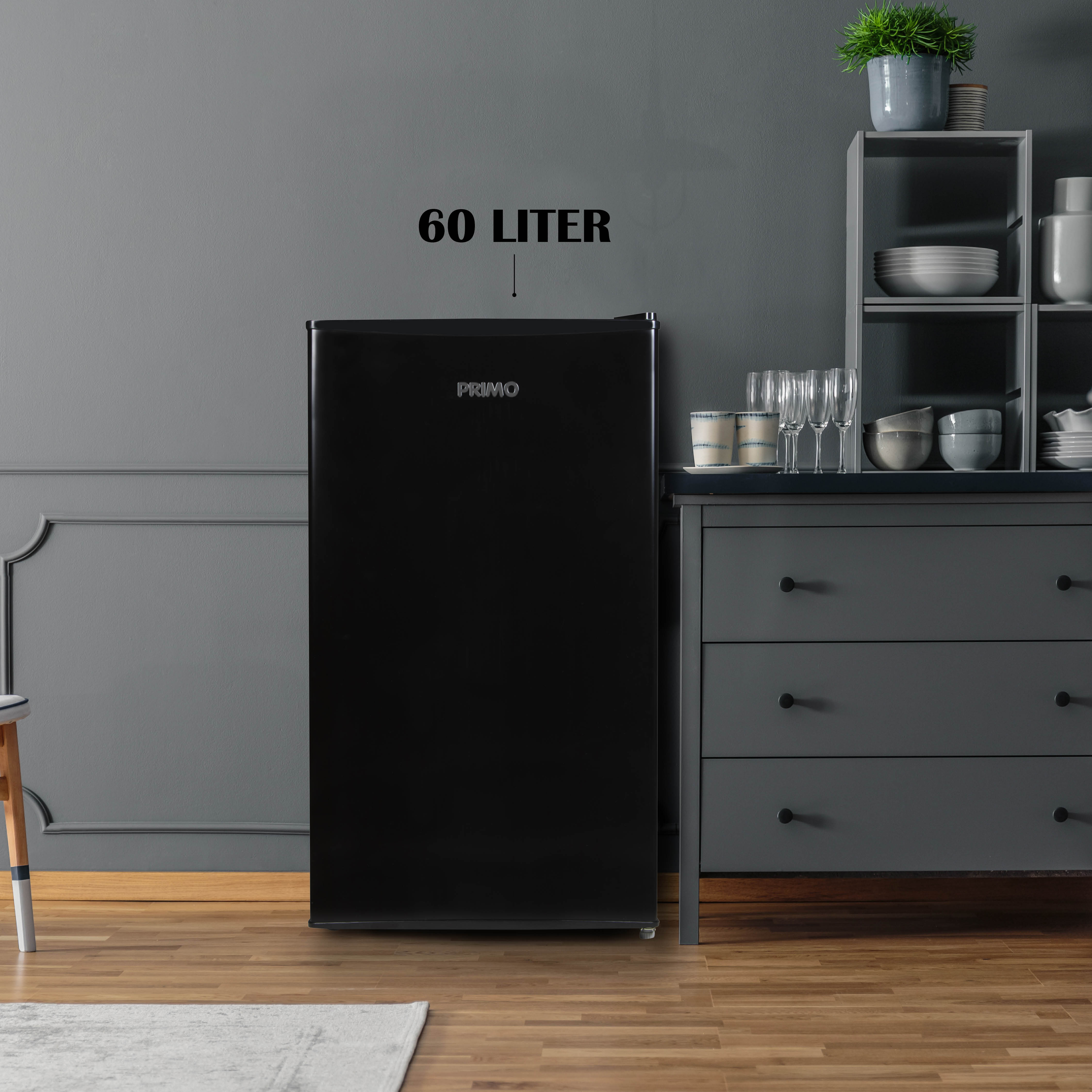 Zwarte koelkast met de tekst '60 LITER'. Staat in een kamer met kasten.