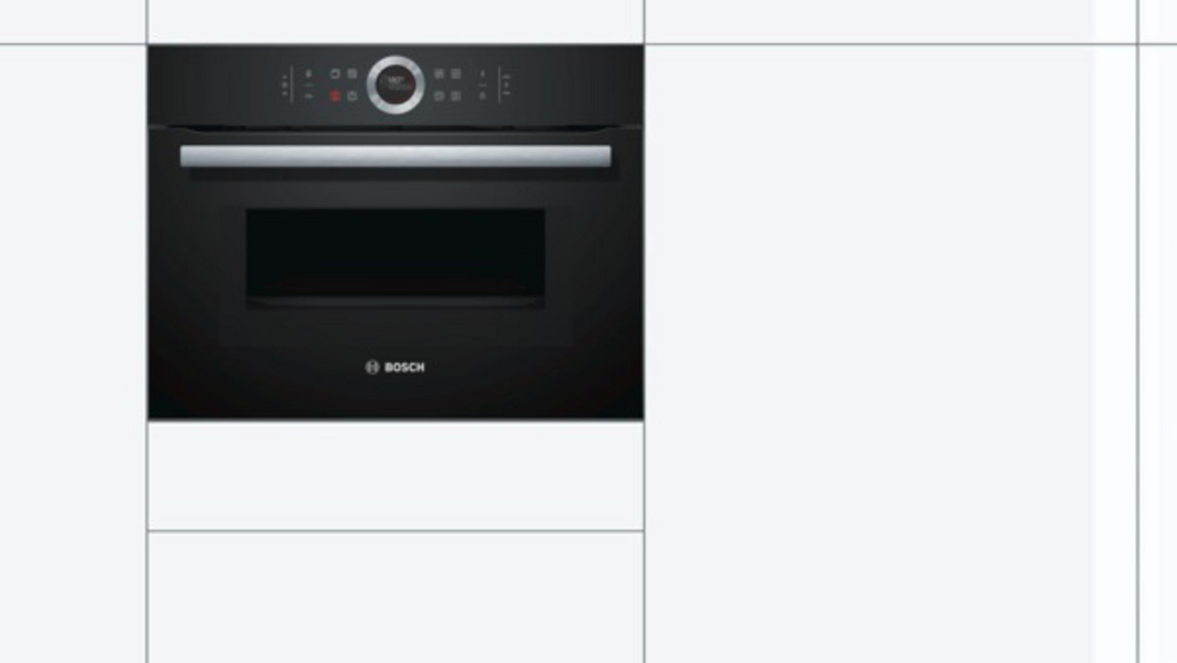 Horno microondas negro en una cocina. Está empotrado en un armario.