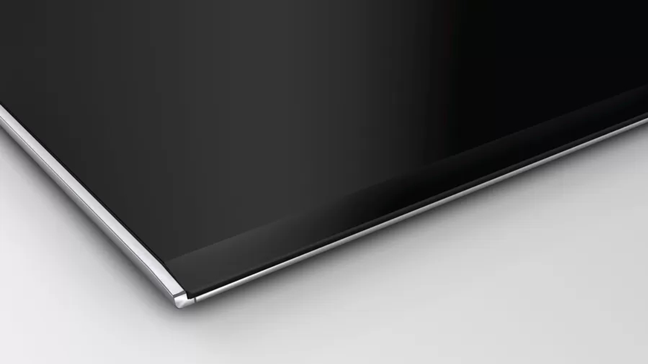 Czarna płyta grzewcza ze srebrnym obramowaniem. Białe tło. Ujęcie z bliska.