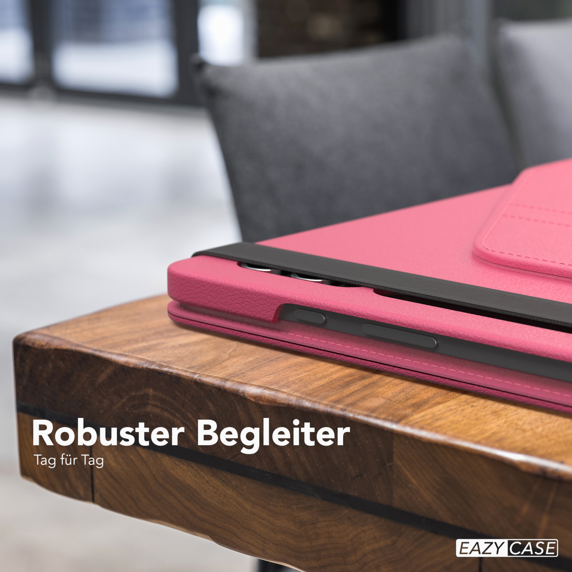 Rosa Tablethülle auf einem Holztisch. Schwarzer Riemen über der Hülle.