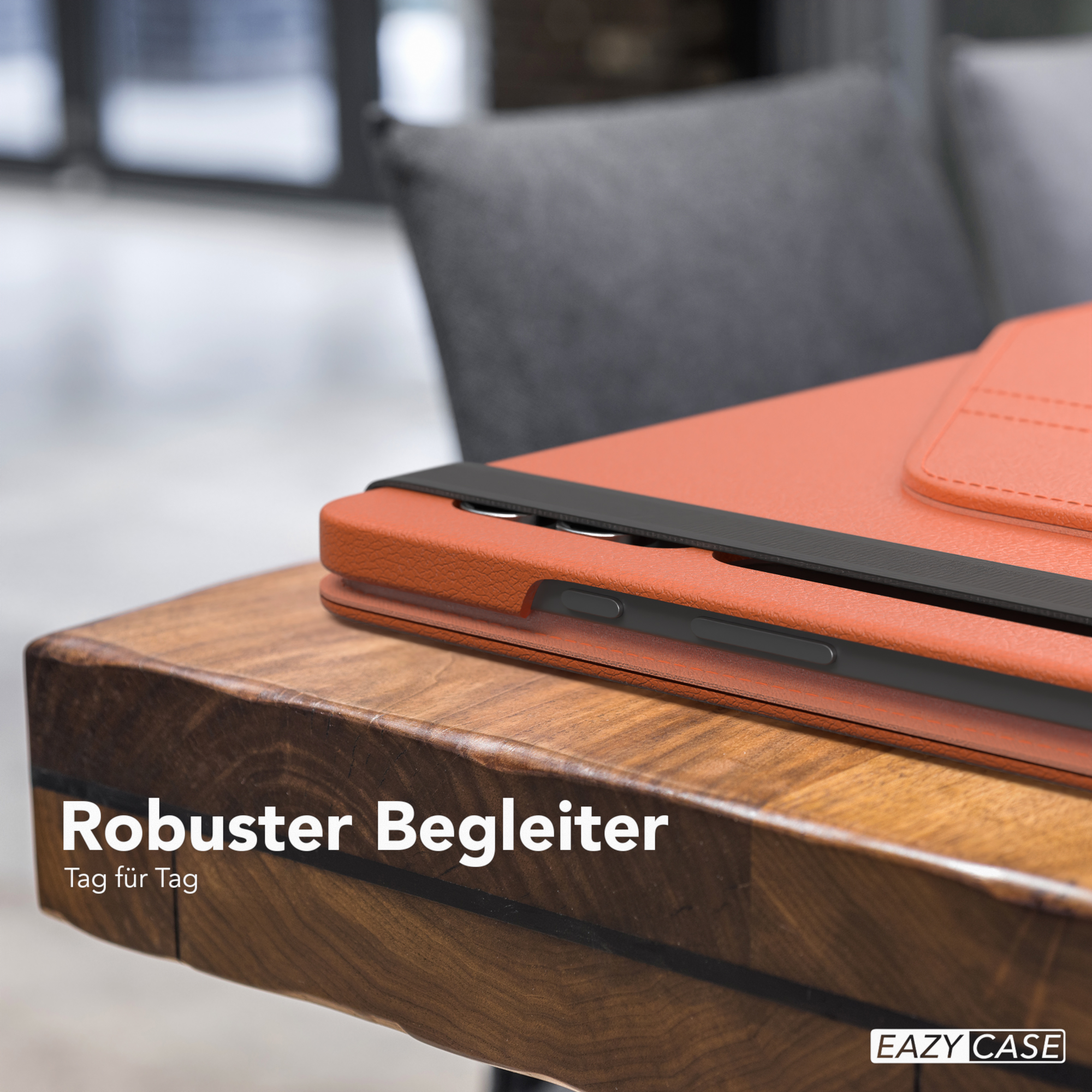 Eine orangefarbene Tablet-Hülle mit schwarzem Riemen, auf einem Holztisch. Text: Robuster Begleiter.