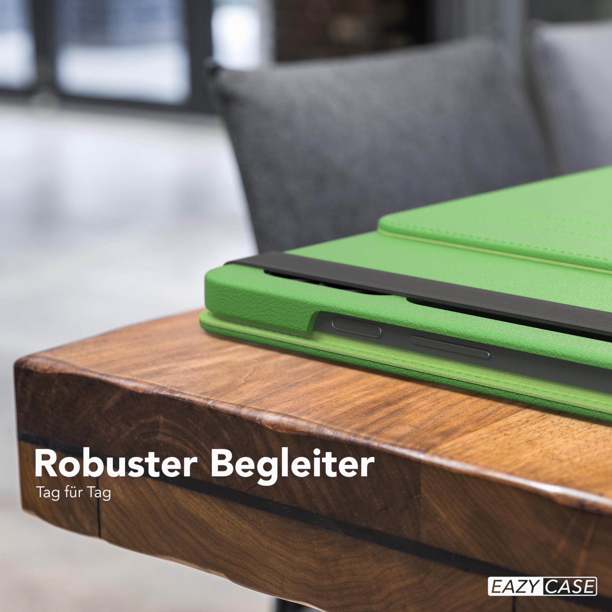 Grüne Tablethülle auf einem Holztisch. Ein schwarzer Riemen sichert das Tablet.