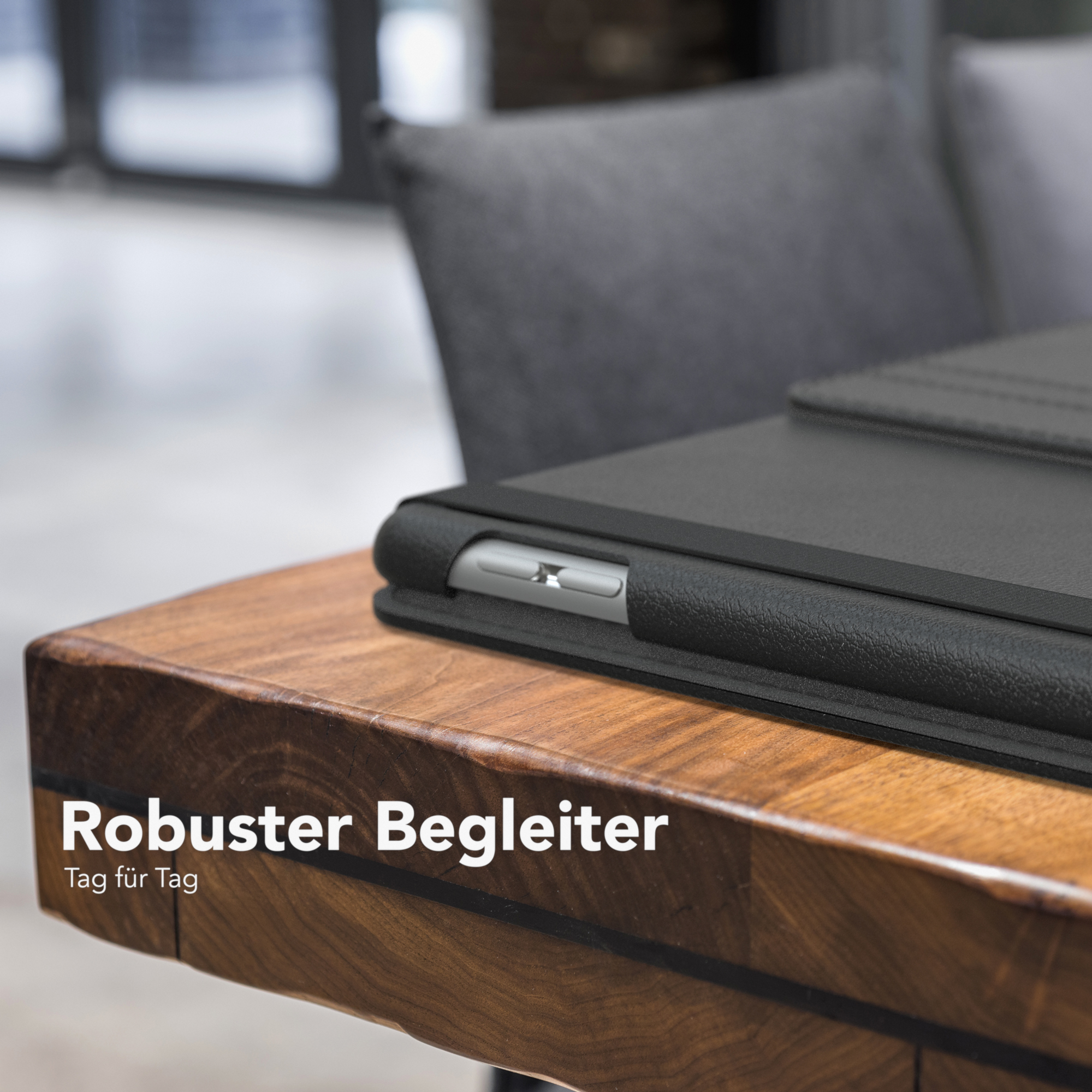 Schwarze Tablet-Hülle auf einem Holztisch mit dem Text „Robuster Begleiter“.