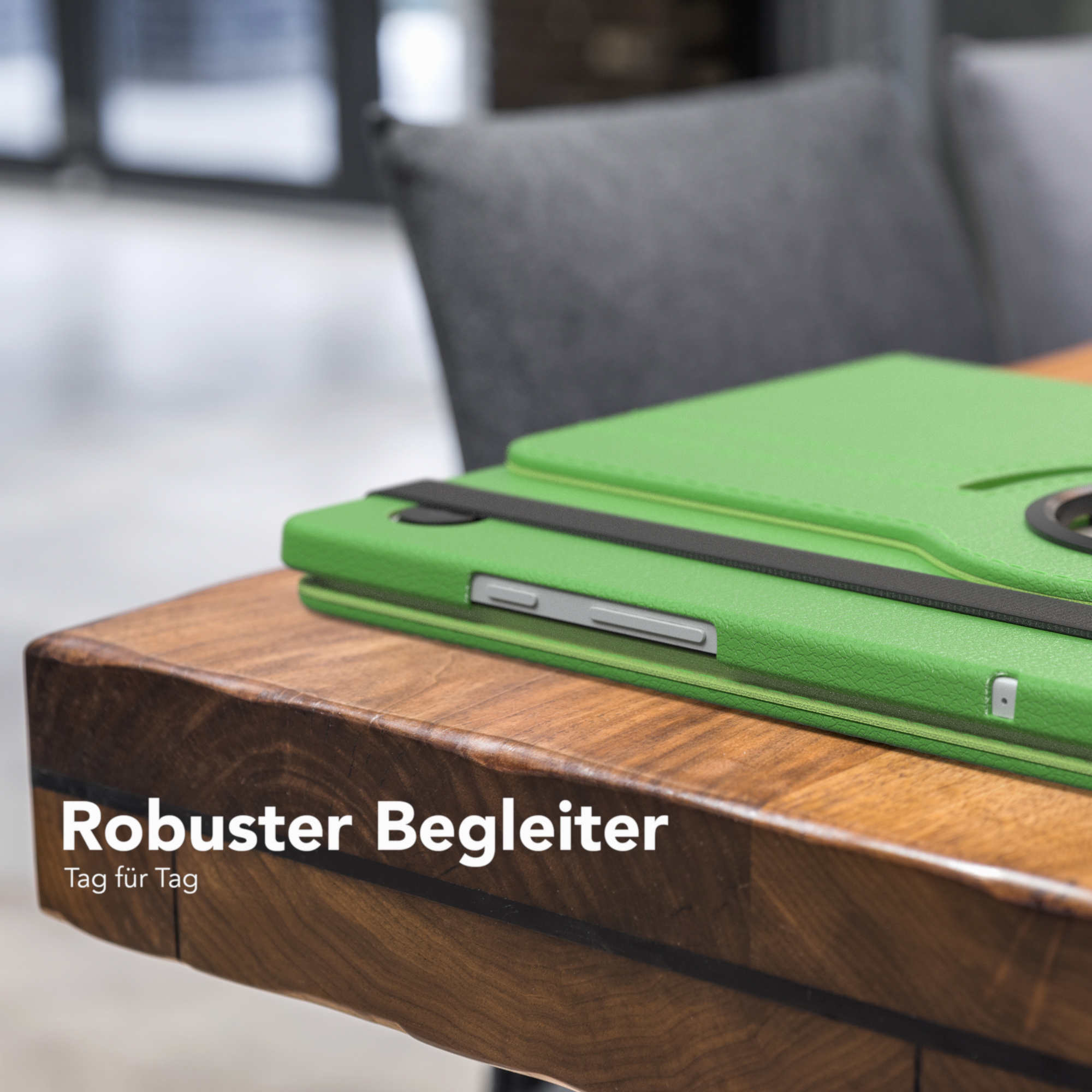 Grüne Tablet-Hülle auf einem Holztisch. Text auf der Hülle lautet: 'Robuster Begleiter'.