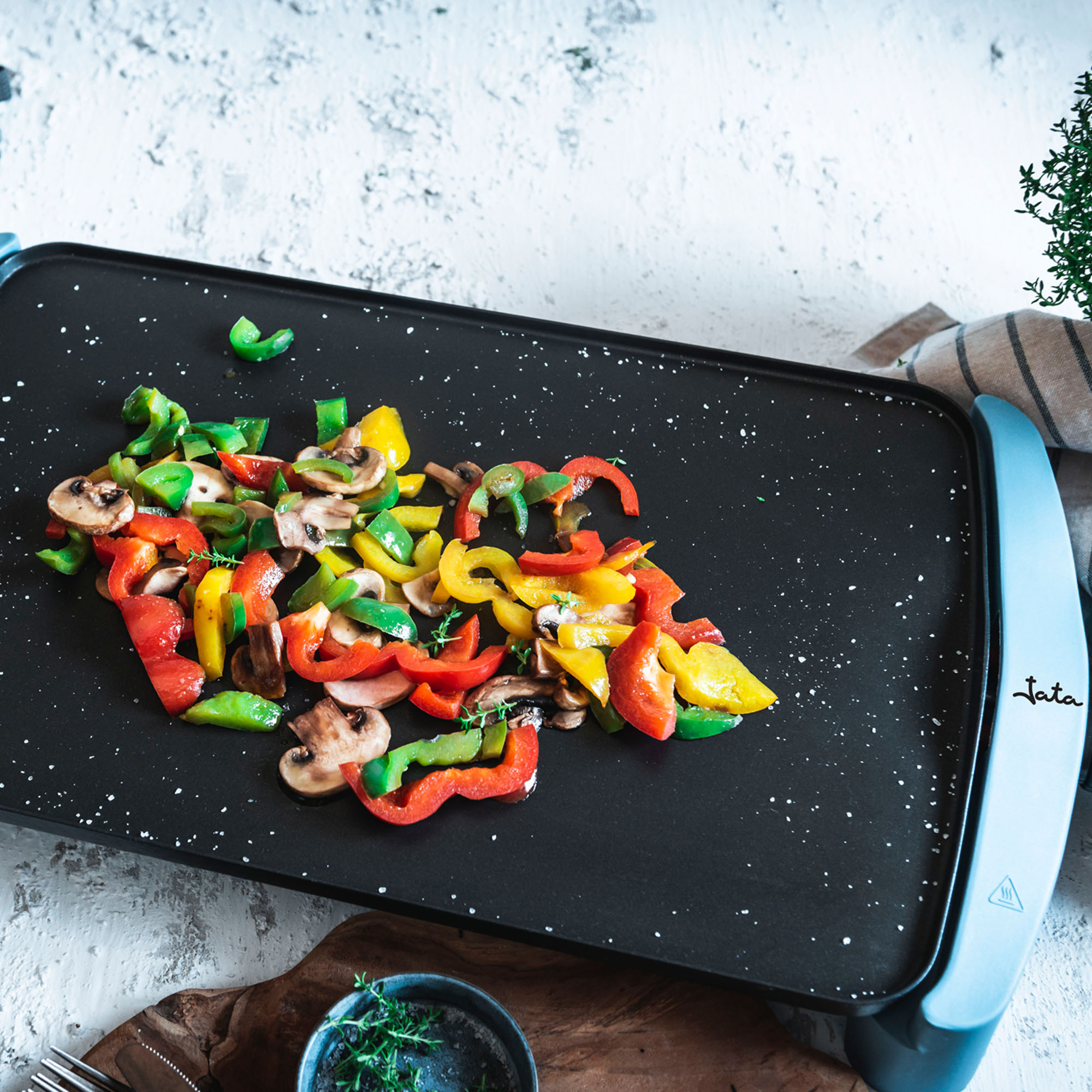 Verduras a la plancha en plancha negra, ingredientes visibles.