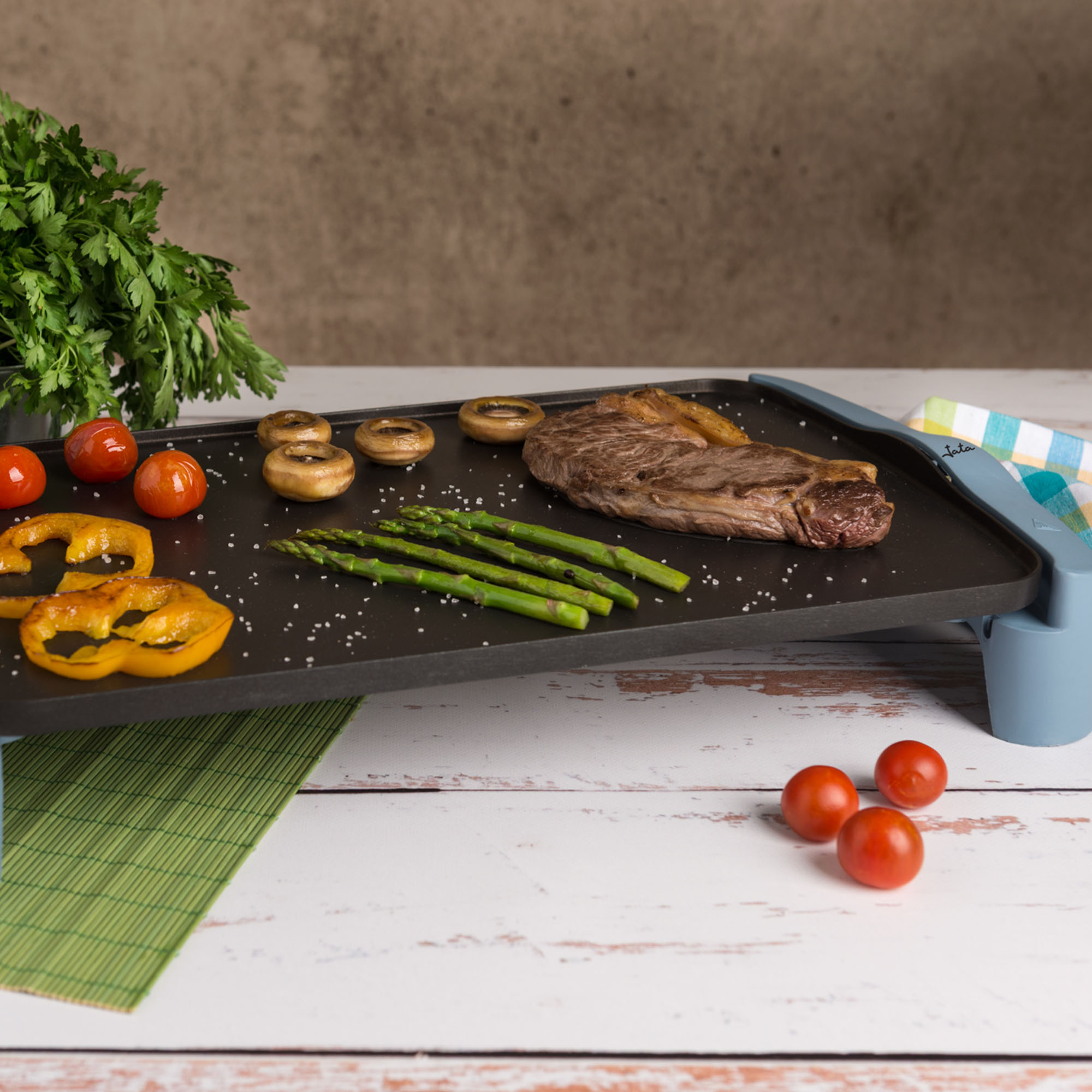 Filete a la parrilla, verduras y hierbas en una plancha, con tomates y perejil.