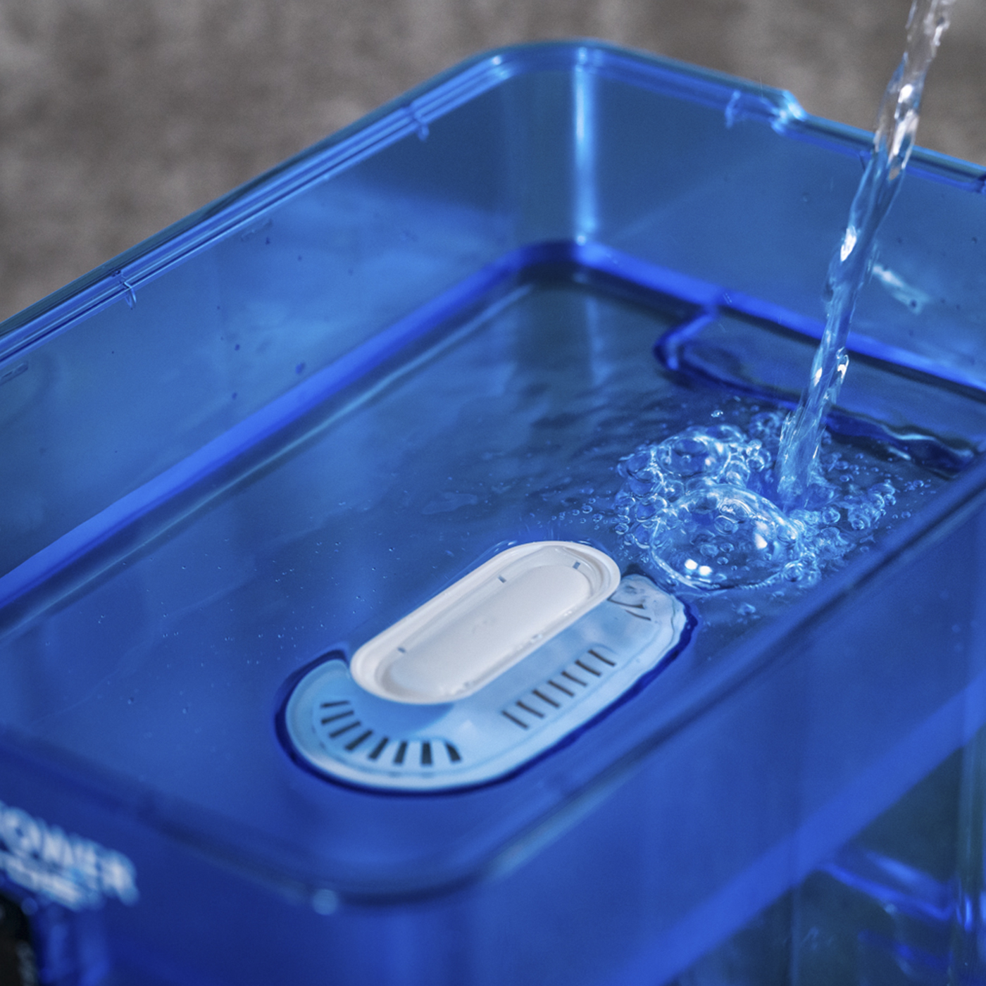 Agua azul vertiéndose en un recipiente azul con un filtro blanco.