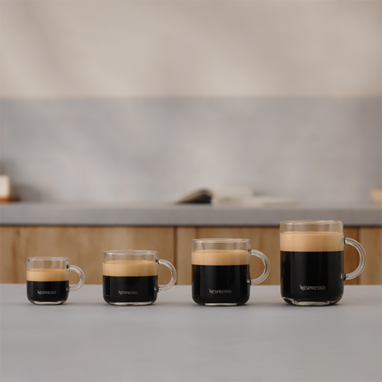 Vier Espressotassen aus Glas auf einem Tisch, unterschiedliche Größen.