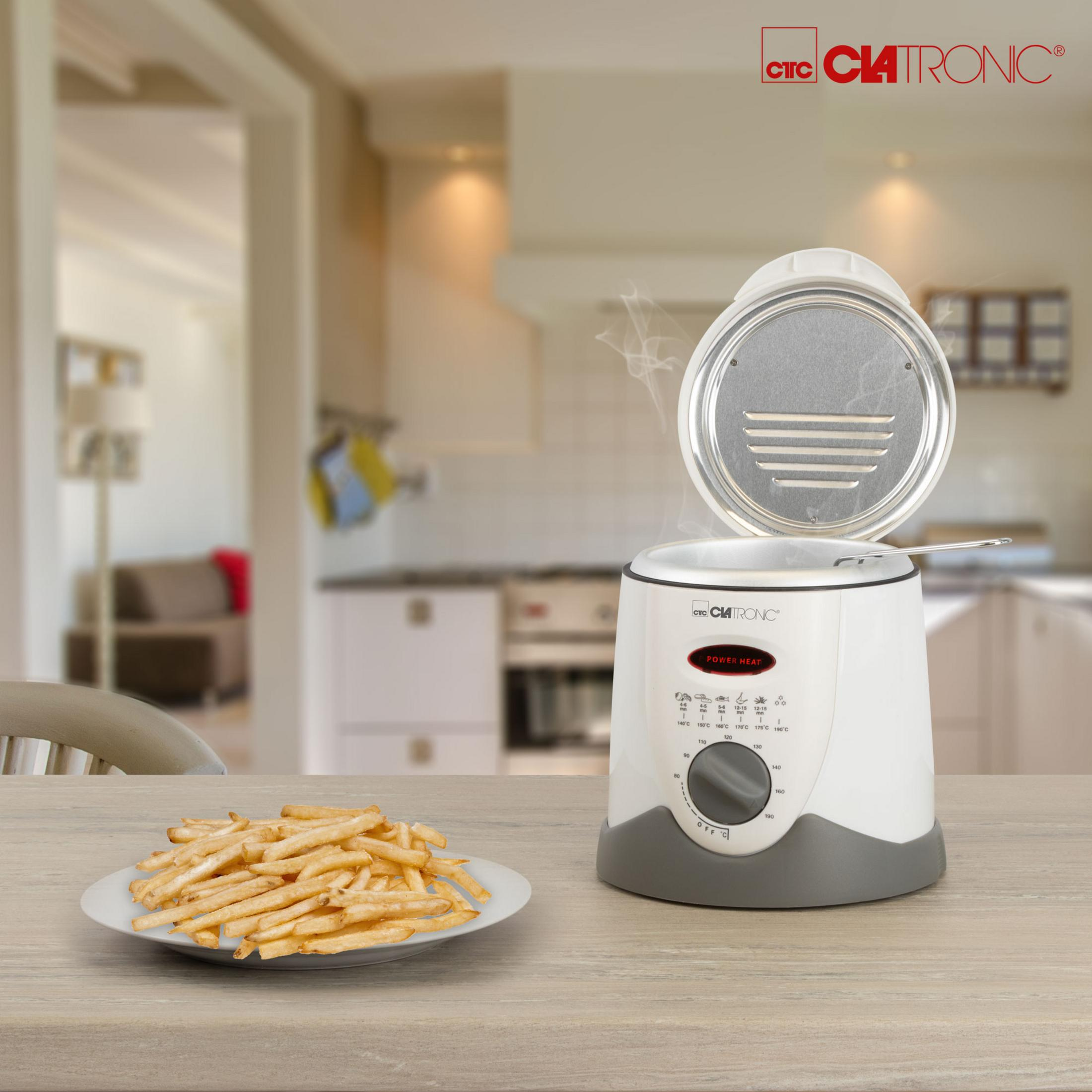 Biała frytkownica z otwartą pokrywą. Frytki na talerzu, tło kuchni.