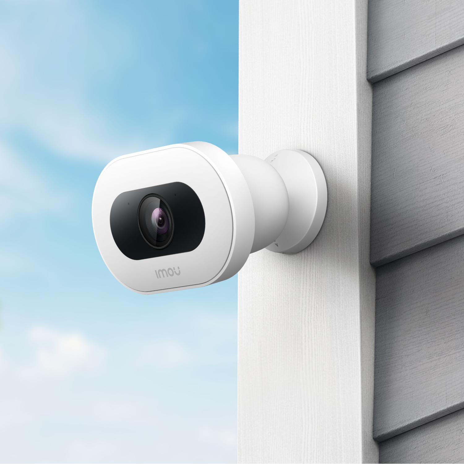 Biała kamera bezpieczeństwa na białej ścianie, tle niebieskiego nieba. Czarny obiektyw i nazwa marki.