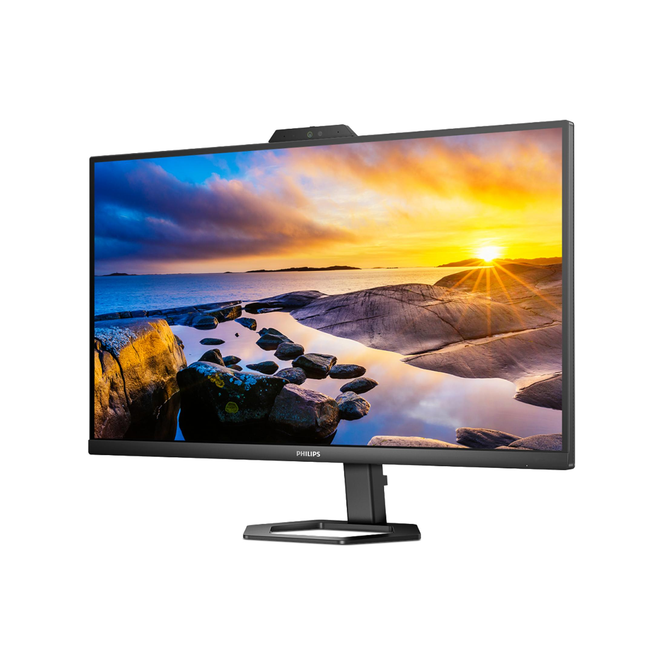 A large monitor with a sunset over a rocky coastline. A webcam is on top.