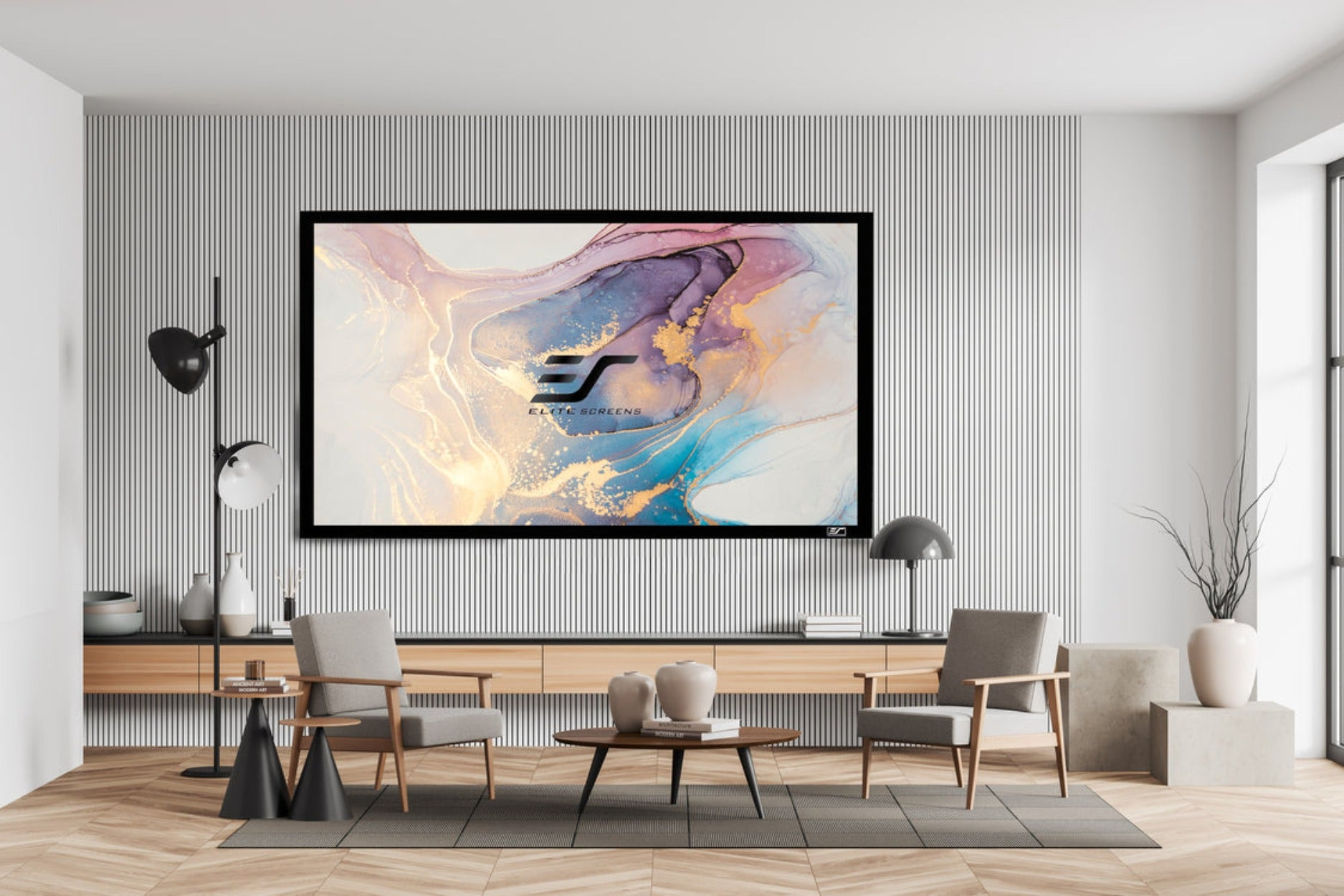 Una sala de estar con una pantalla grande, sillas y una mesa, decorada en tonos neutros.