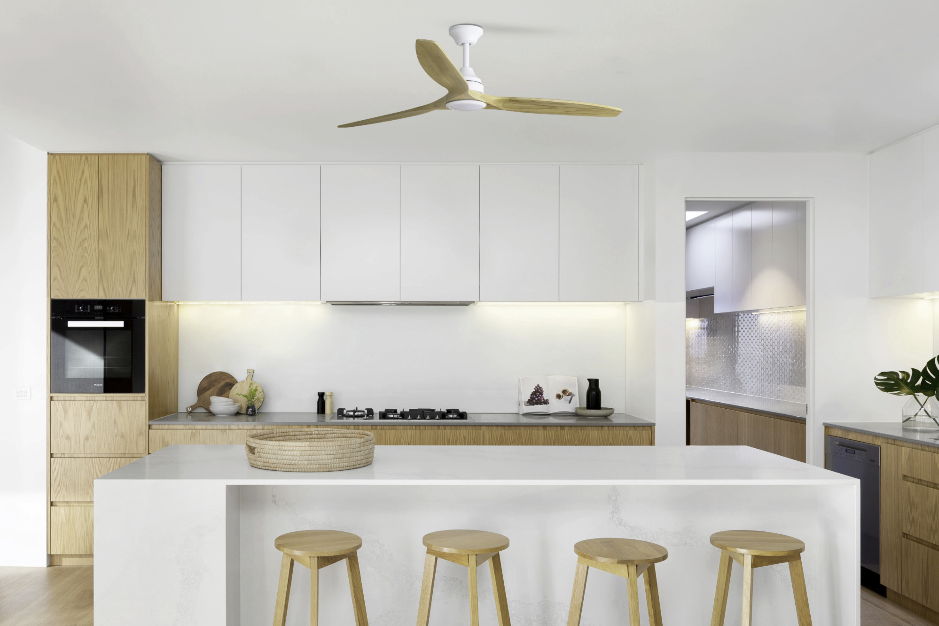 Moderne Küche mit weißen Schränken, Holzakzenten, Insel mit Hockern und Deckenventilator.