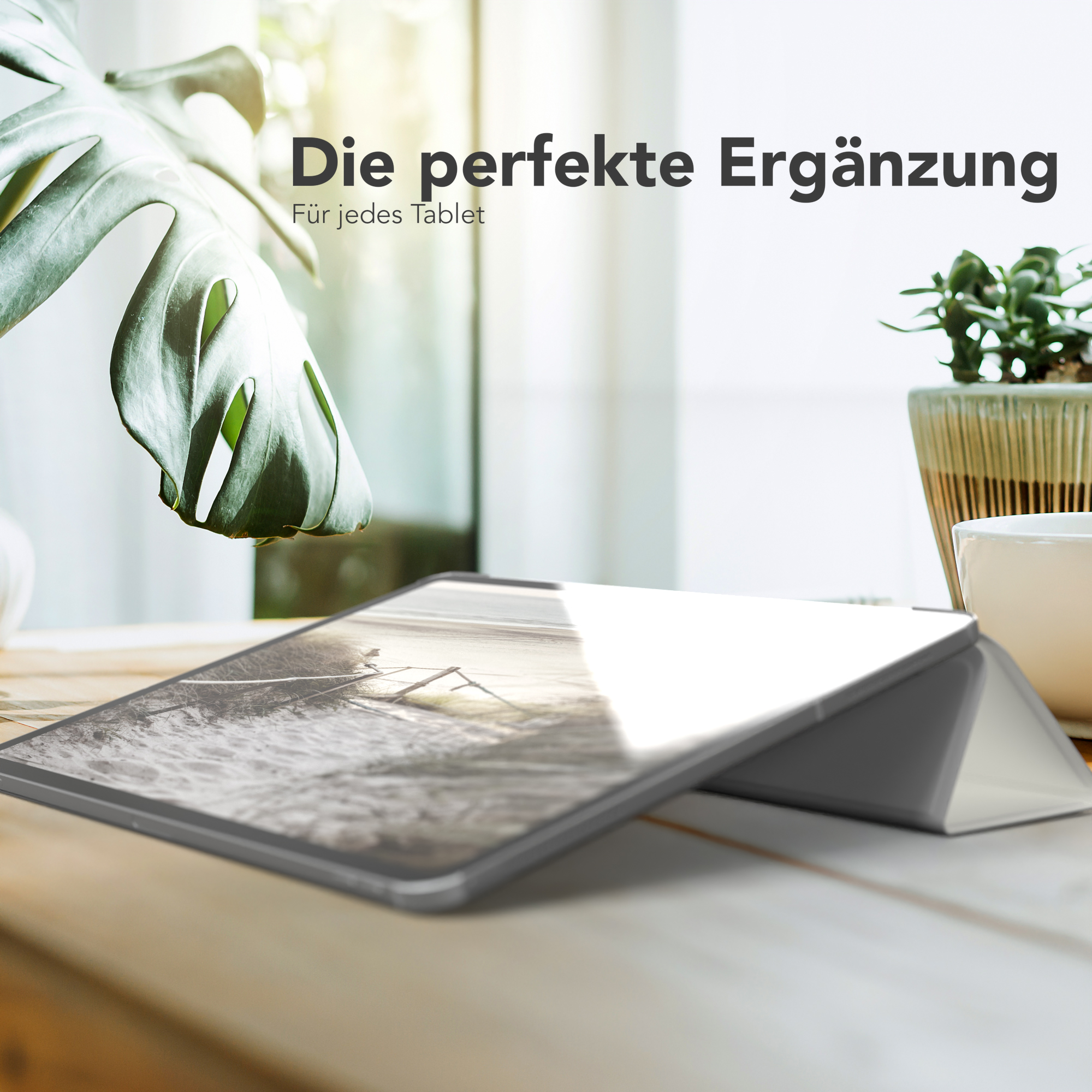 Tablet in einem Ständer. Pflanze und Fenster im Hintergrund. Text oben: Die perfekte Ergänzung.