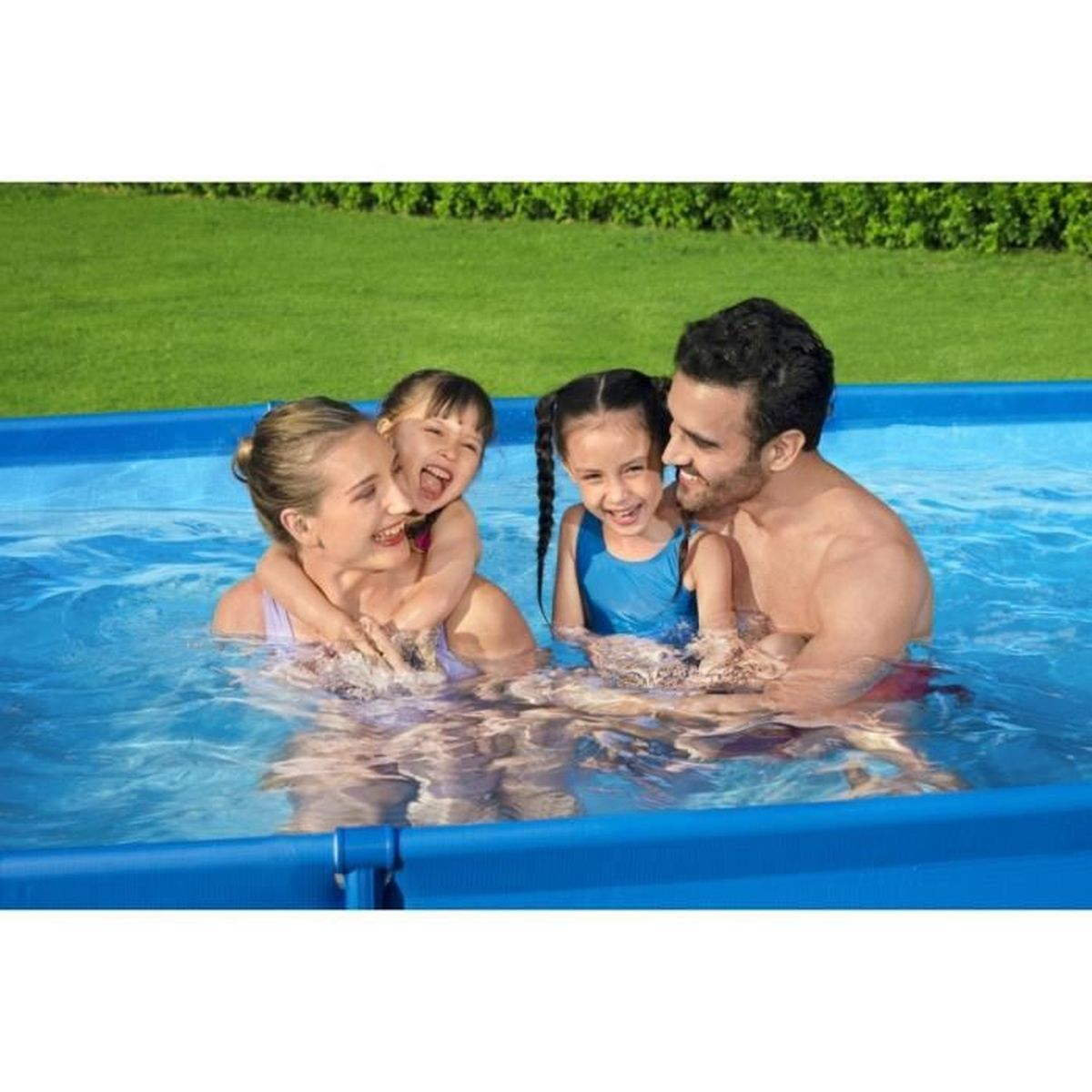 Vierköpfige Familie in blauem Pool, lächelt. Grüner Rasen im Hintergrund.