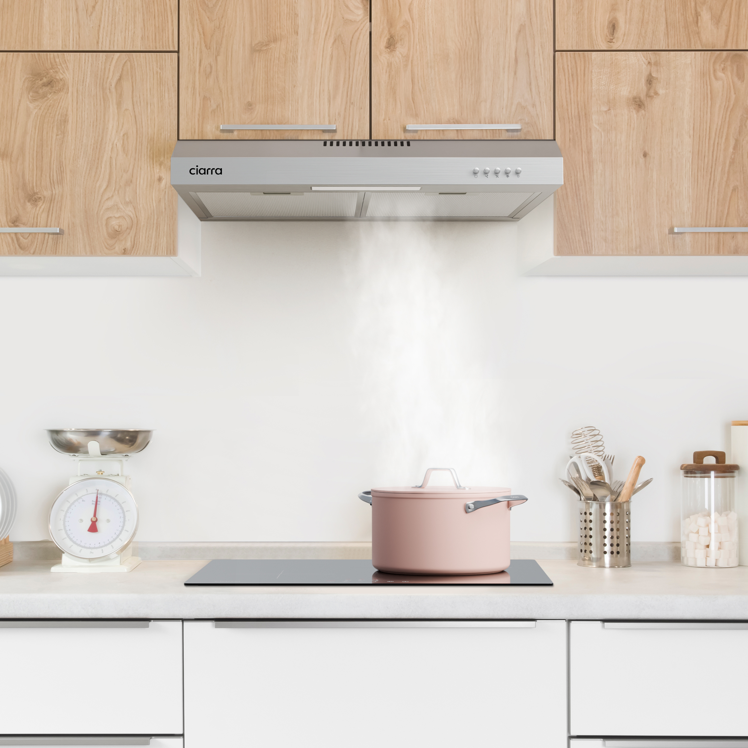 Keuken met afzuigkap boven een fornuis, roze pot op het fornuis. Houten kasten.
