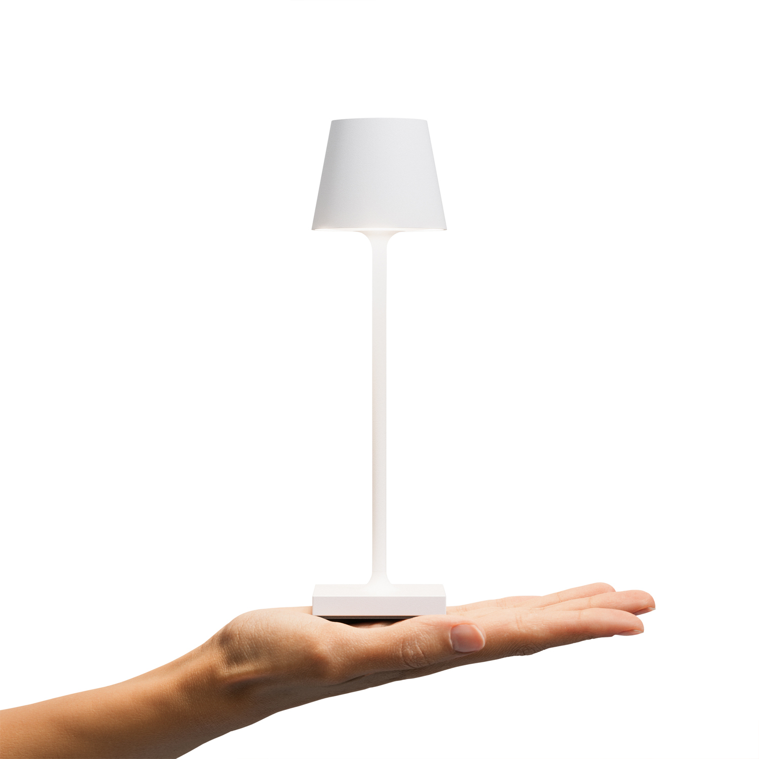 Eine kleine weiße Lampe, die von einer Hand gehalten wird. Die Lampe steht auf einem weißen Sockel.