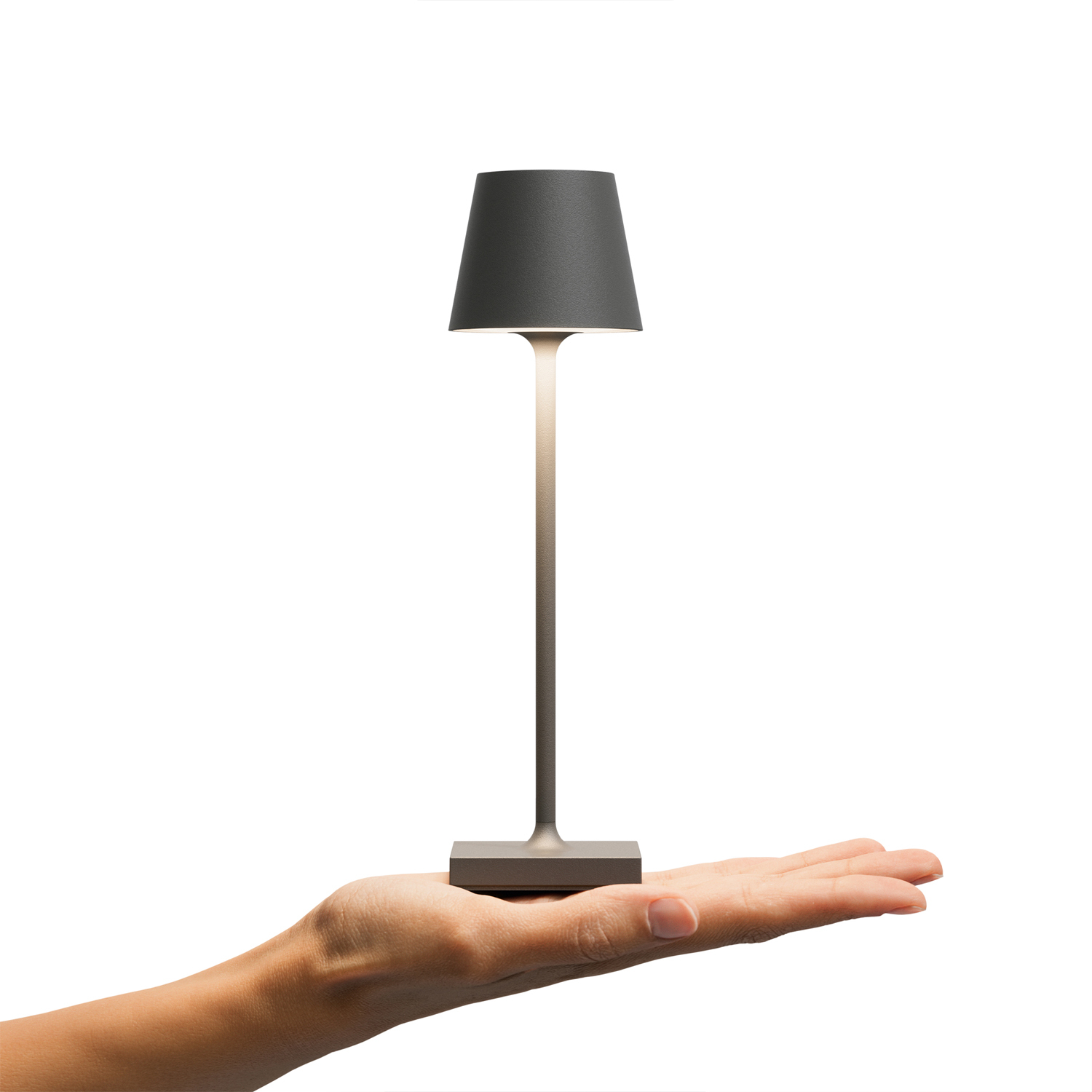Eine kleine graue Lampe auf grauem Sockel, gehalten von einer Hand. Sie hat einen Schirm und Stiel.