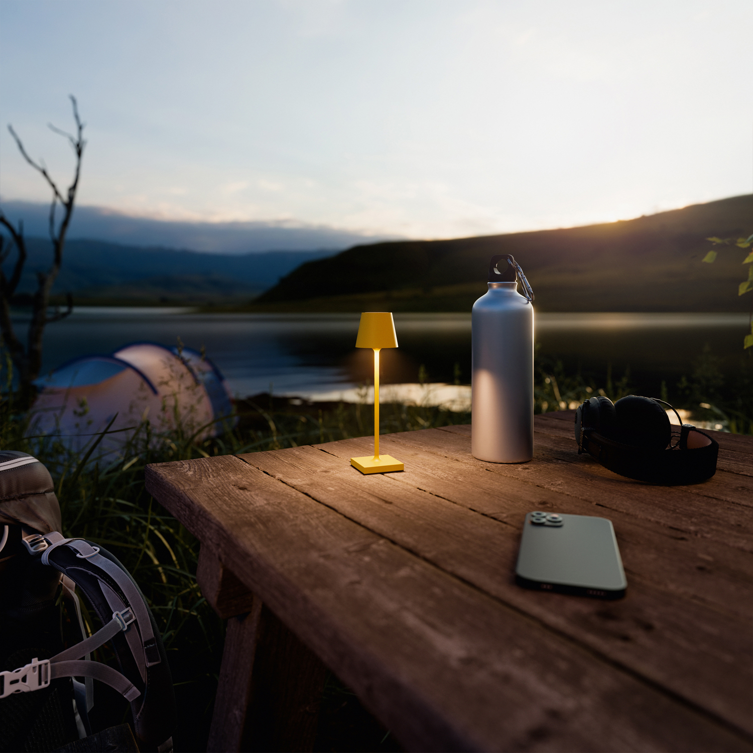 Gelbe Schreibtischlampe, Wasserflasche, Telefon und Kopfhörer auf einem Holztisch am See.