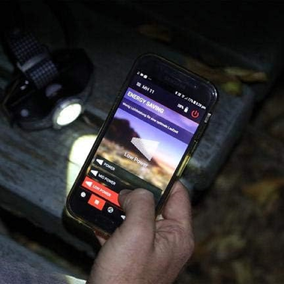 Smartphone in der Hand, zeigt Energiesparoptionen. Bildschirm zeigt Energiesparmodus.