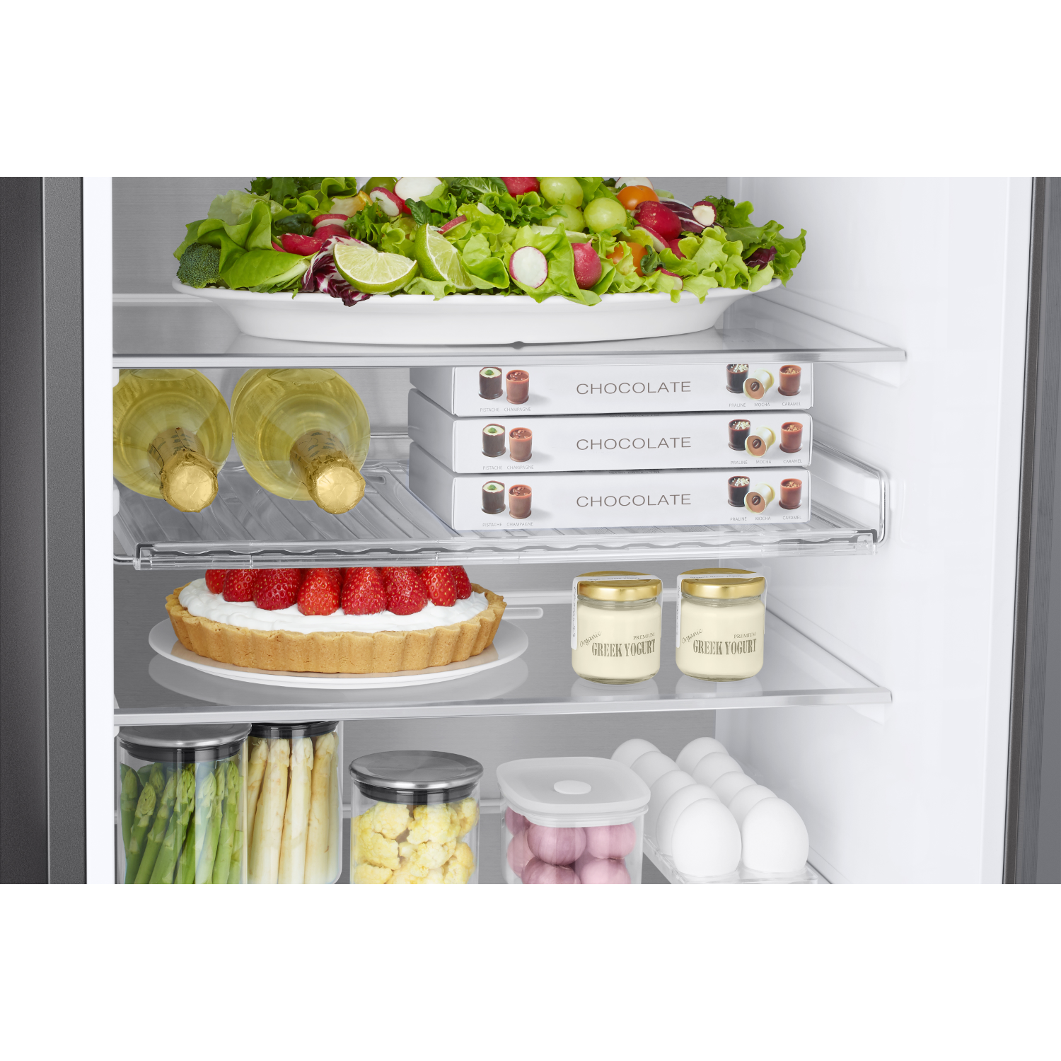 All'interno di un frigorifero con cibo: insalata, fragole, yogurt, cioccolato, uova, vino.