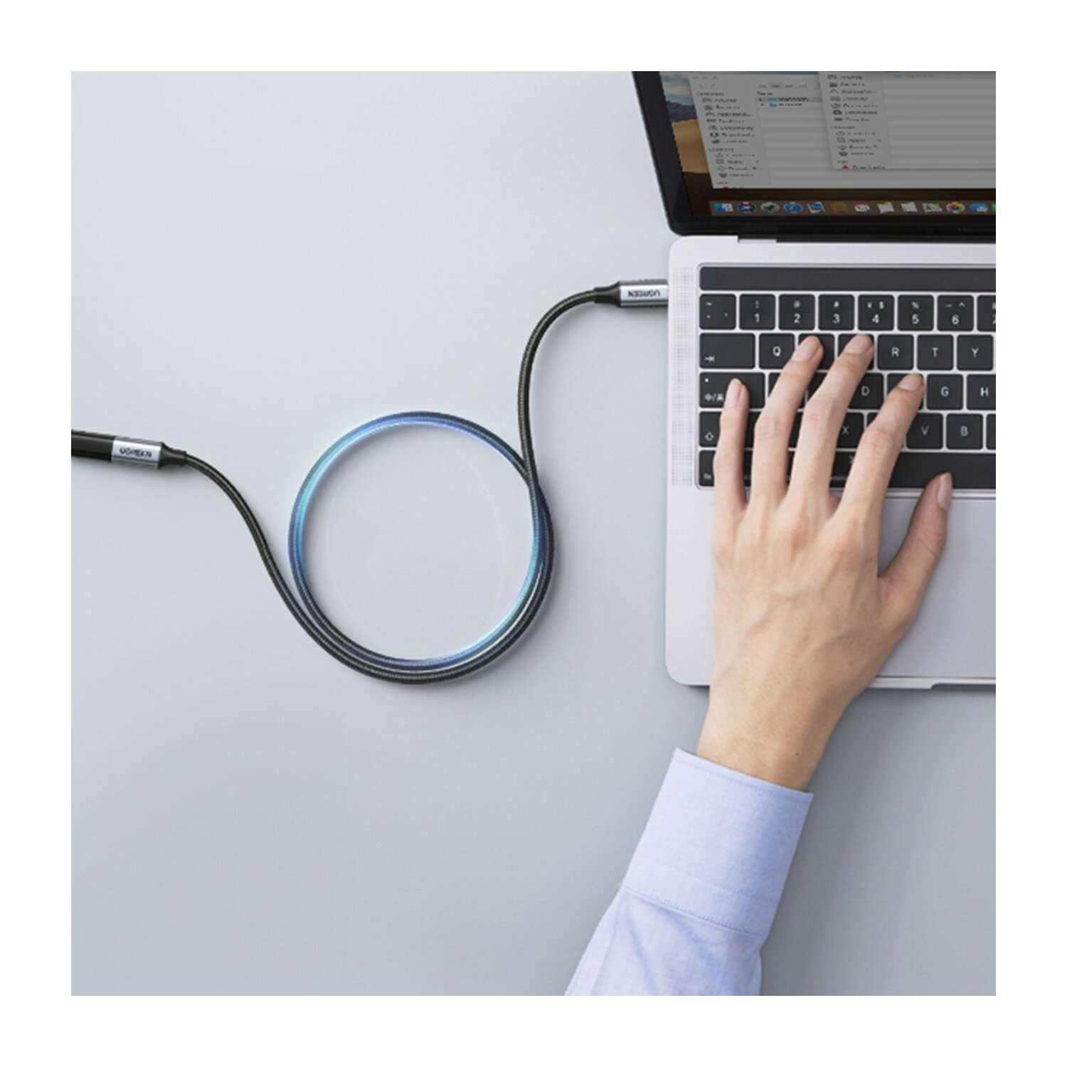 Una mano usa un laptop, un cavo collegato al lato, e un anello luminoso.