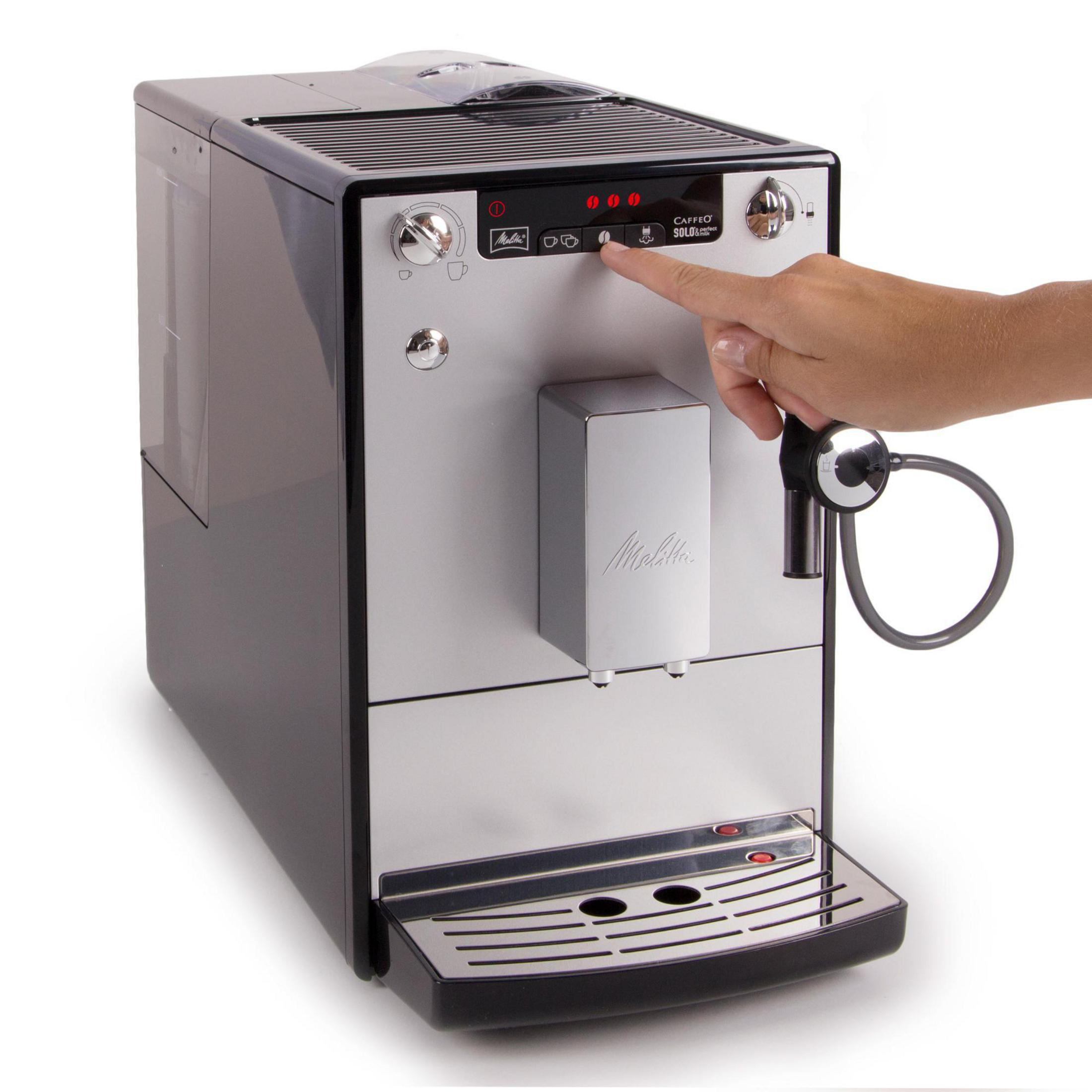 Silber-schwarze Kaffeemaschine. Eine Hand drückt eine Taste auf dem Bedienfeld.