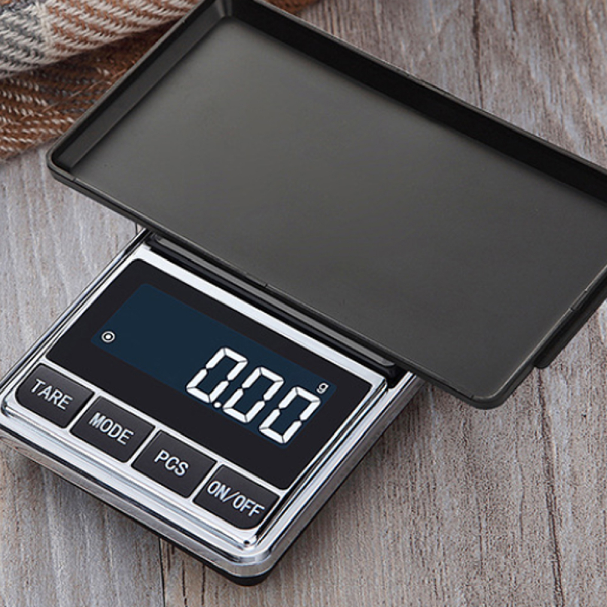 Eine Digitalwaage mit '0.00' Anzeige. Sie ist geöffnet, mit Deckel und liegt auf Holzoberfläche.