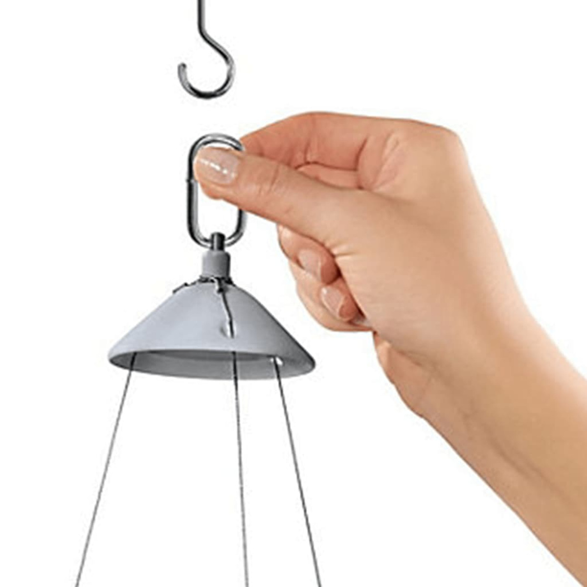 Hand, die den Haken eines hängenden Windspiels einstellt. Silberner Haken und Halterung, weißer Hintergrund.