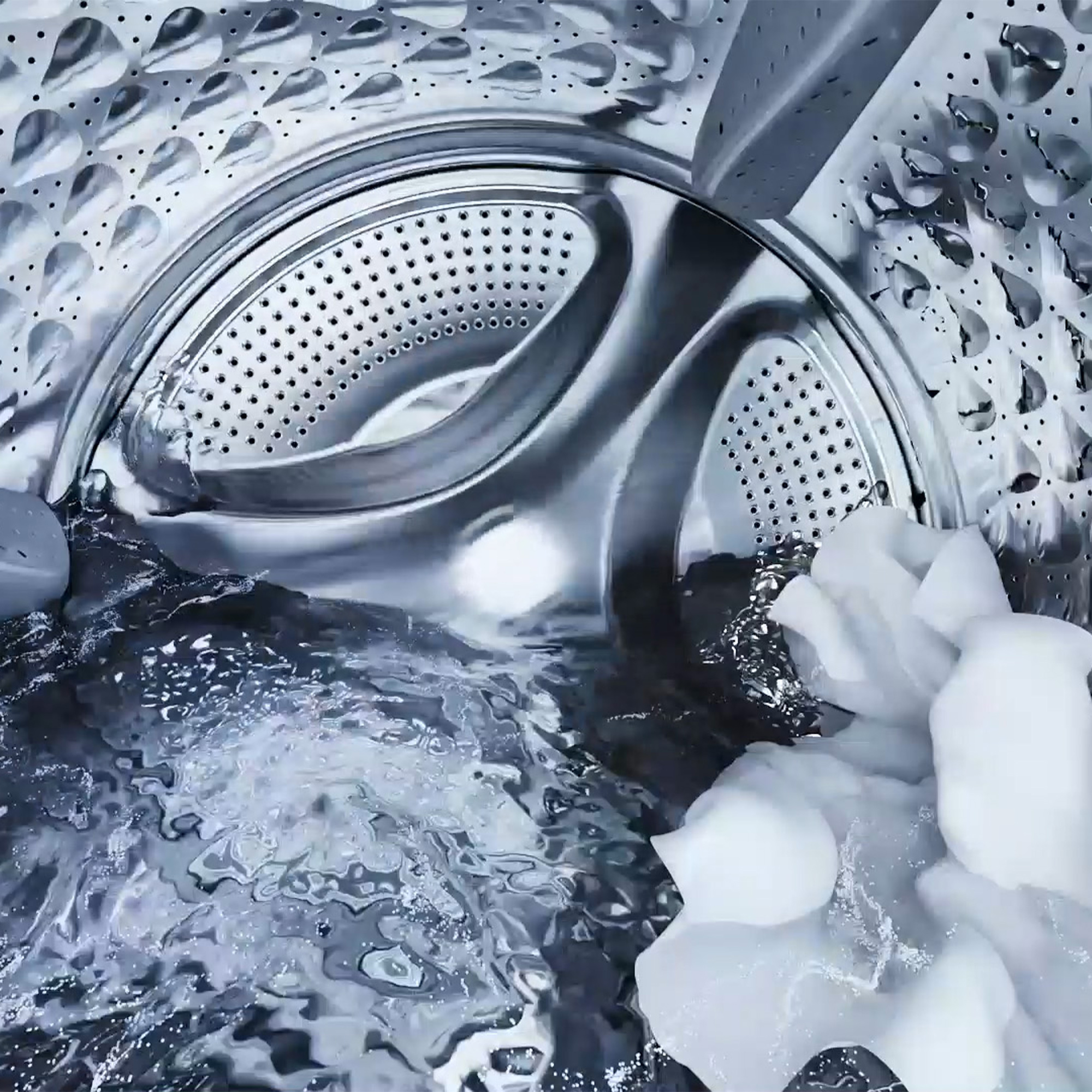 In der Waschmaschine: Wasser, weiße Kleidung und die metallische, perforierte Trommel.