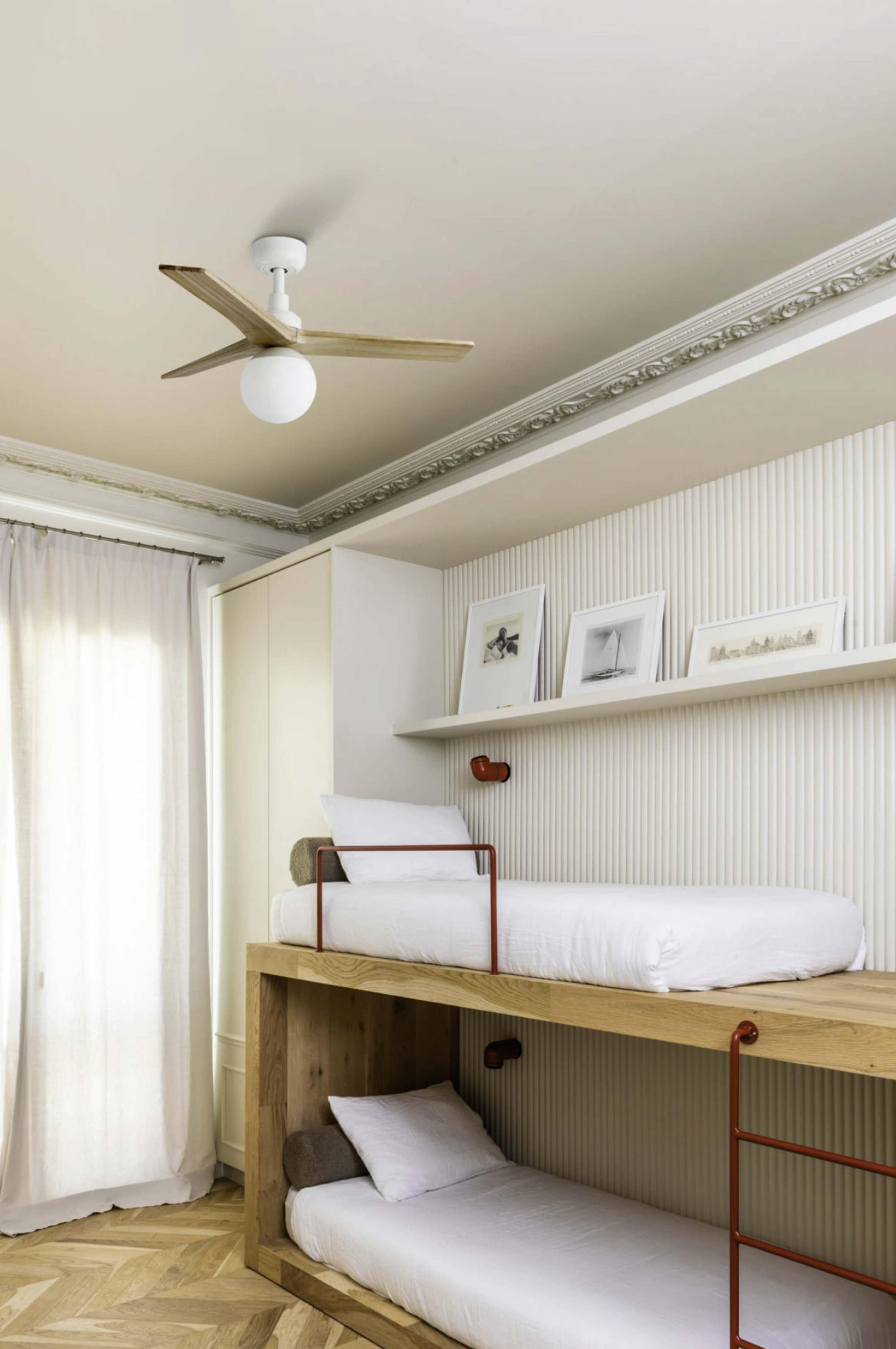 Moderne Etagenbetten mit weißer Bettwäsche, Holzakzenten und Deckenventilator.