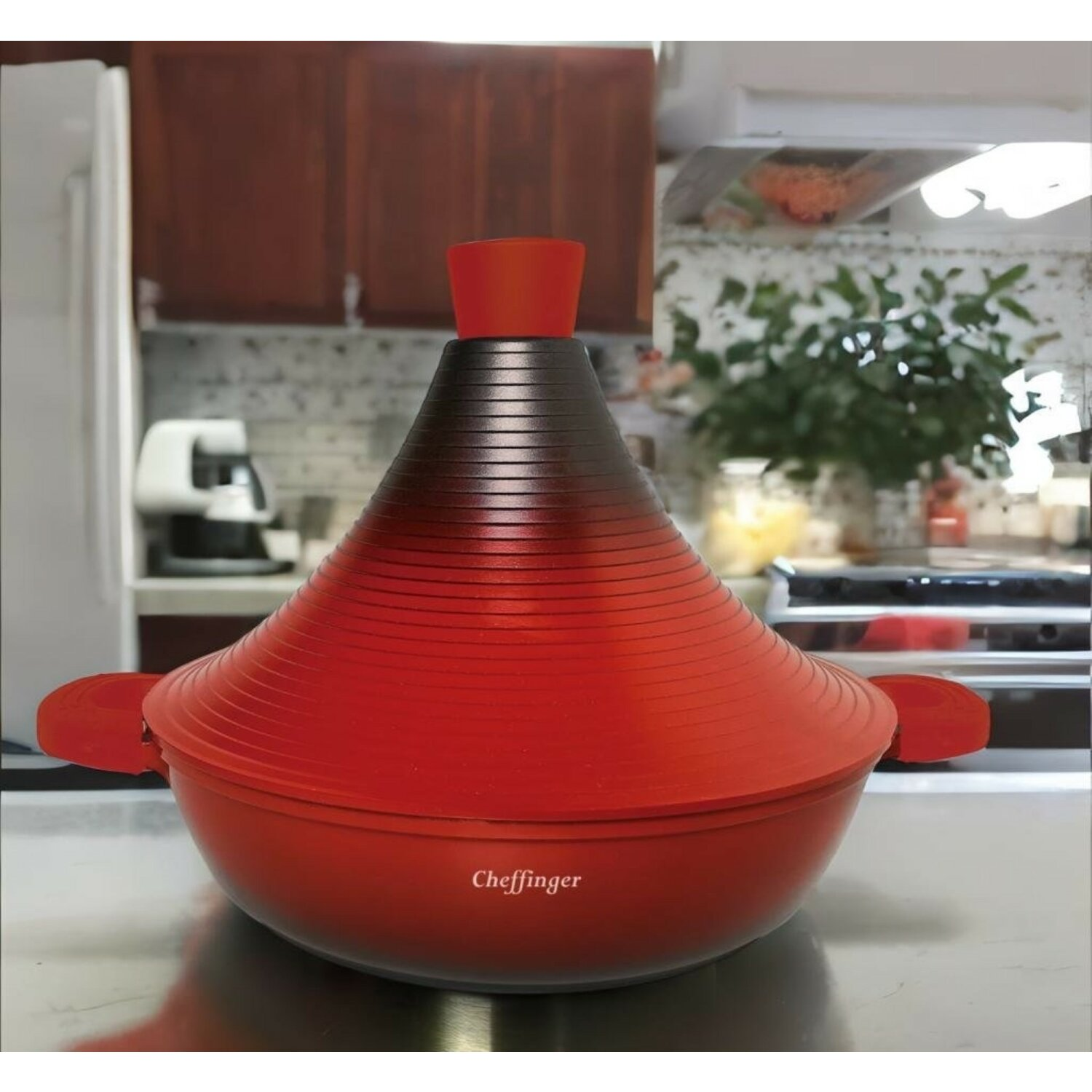 Roter Tagine-Topf mit schwarzem Deckel, auf einer Küchentheke. Küchenhintergrund.