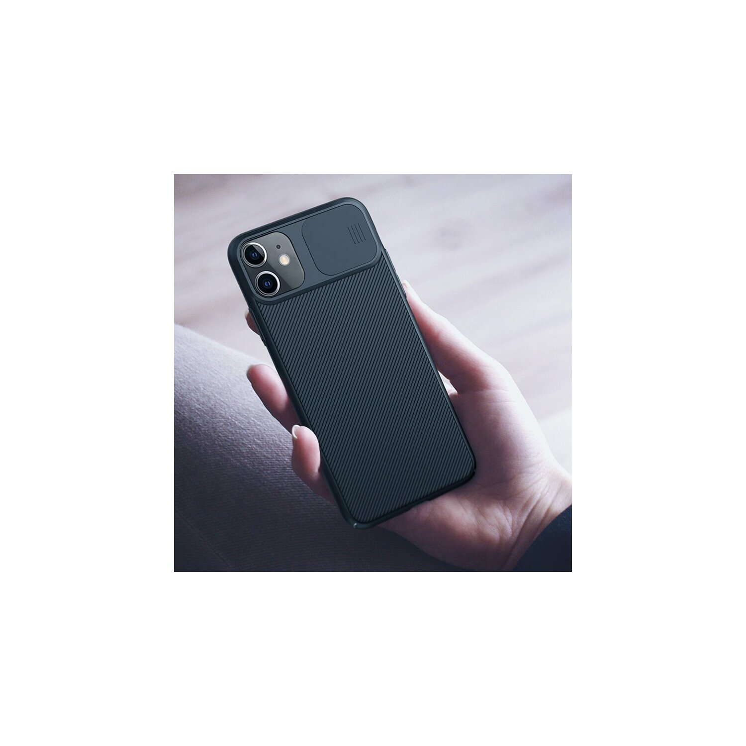 Mano che tiene una custodia per telefono nera. Copertura fotocamera nera. Sfondo bianco.