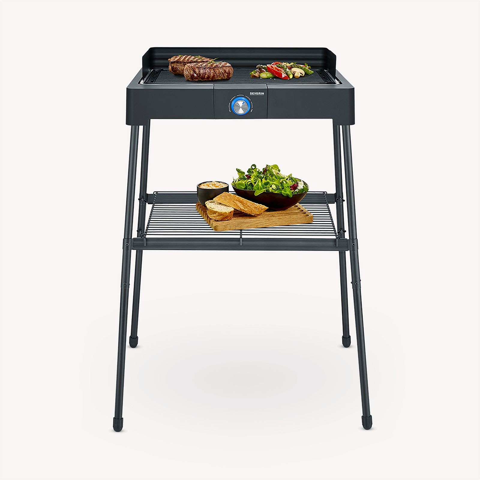 Black and silver grill with steaks and vegetables, with a shelf and food.
