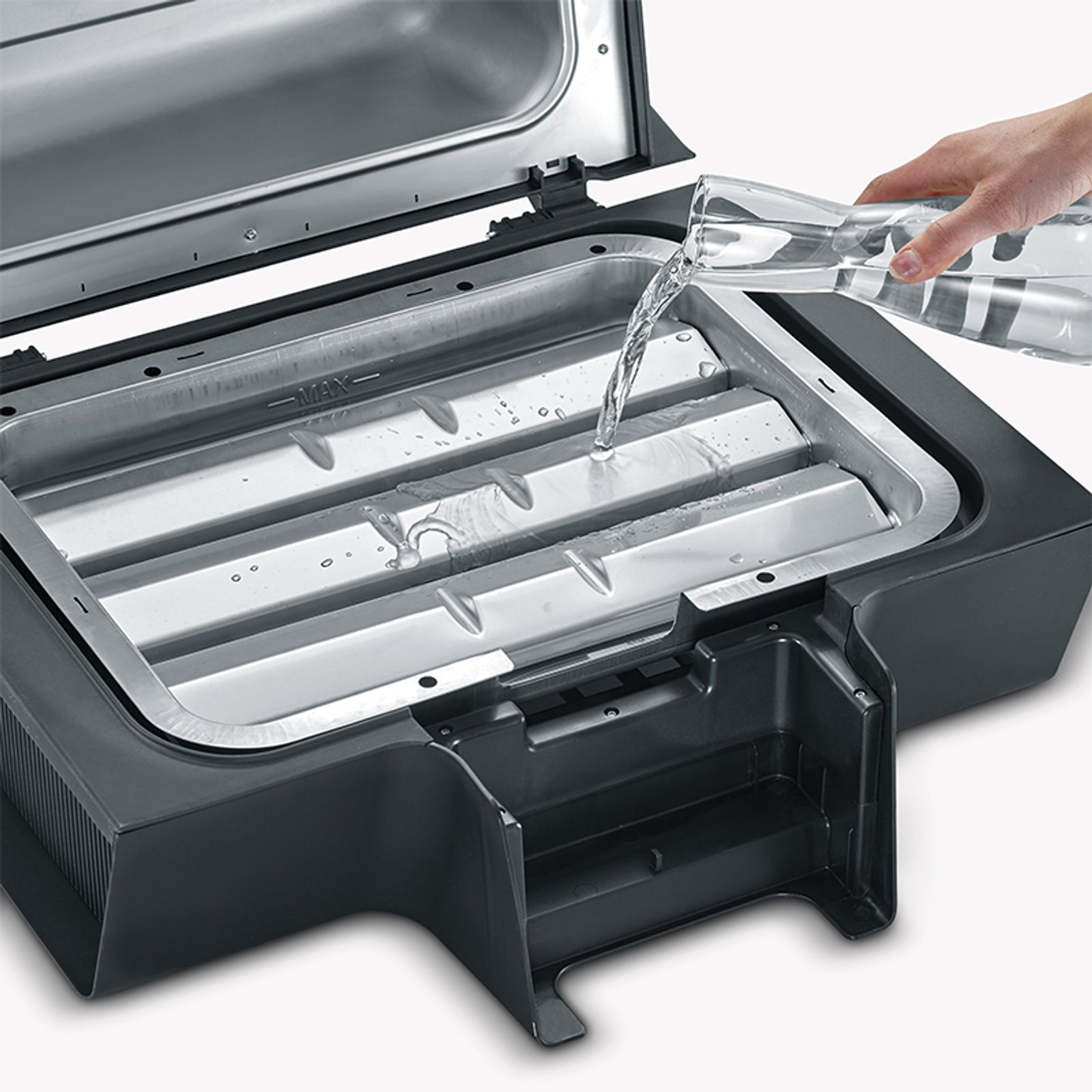 Eine Person gießt Wasser in einen Teil eines Grills. Der Grill ist schwarz und silber.