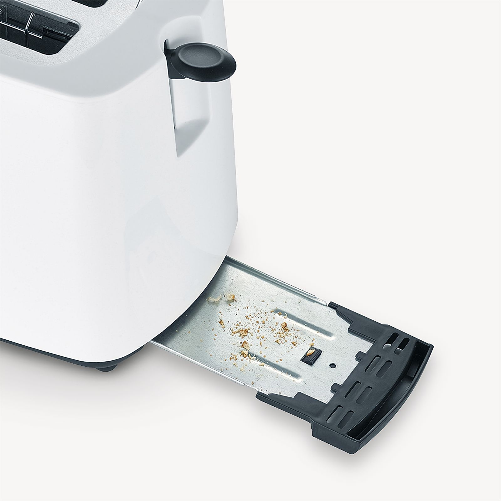 Ein weißer Toaster mit herausgezogener Krümelschublade, die Krümel zeigt. Die Schublade ist schwarz.