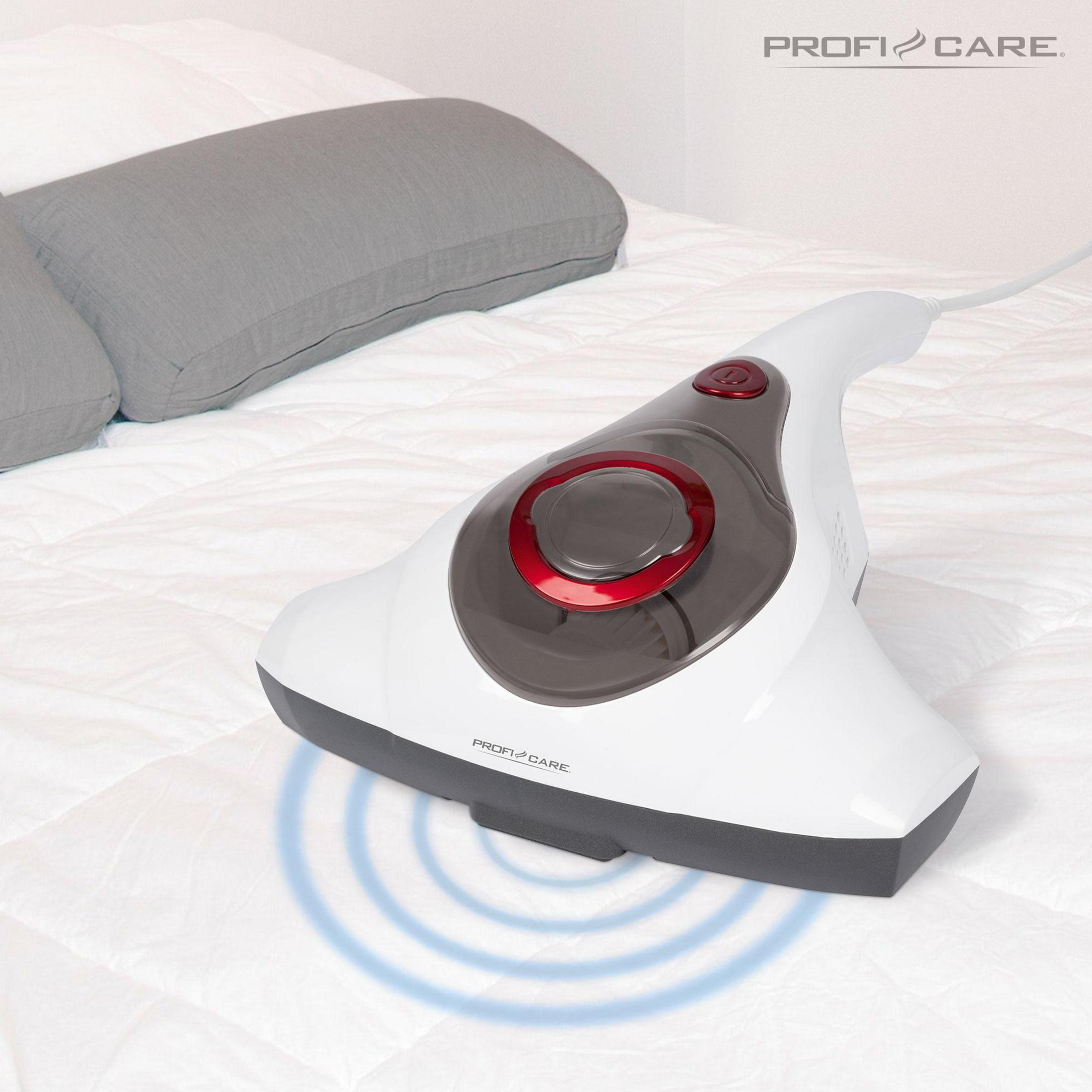 Biały odkurzacz ręczny na łóżku. Urządzenie ma czerwony przycisk i emituje niebieskie fale.