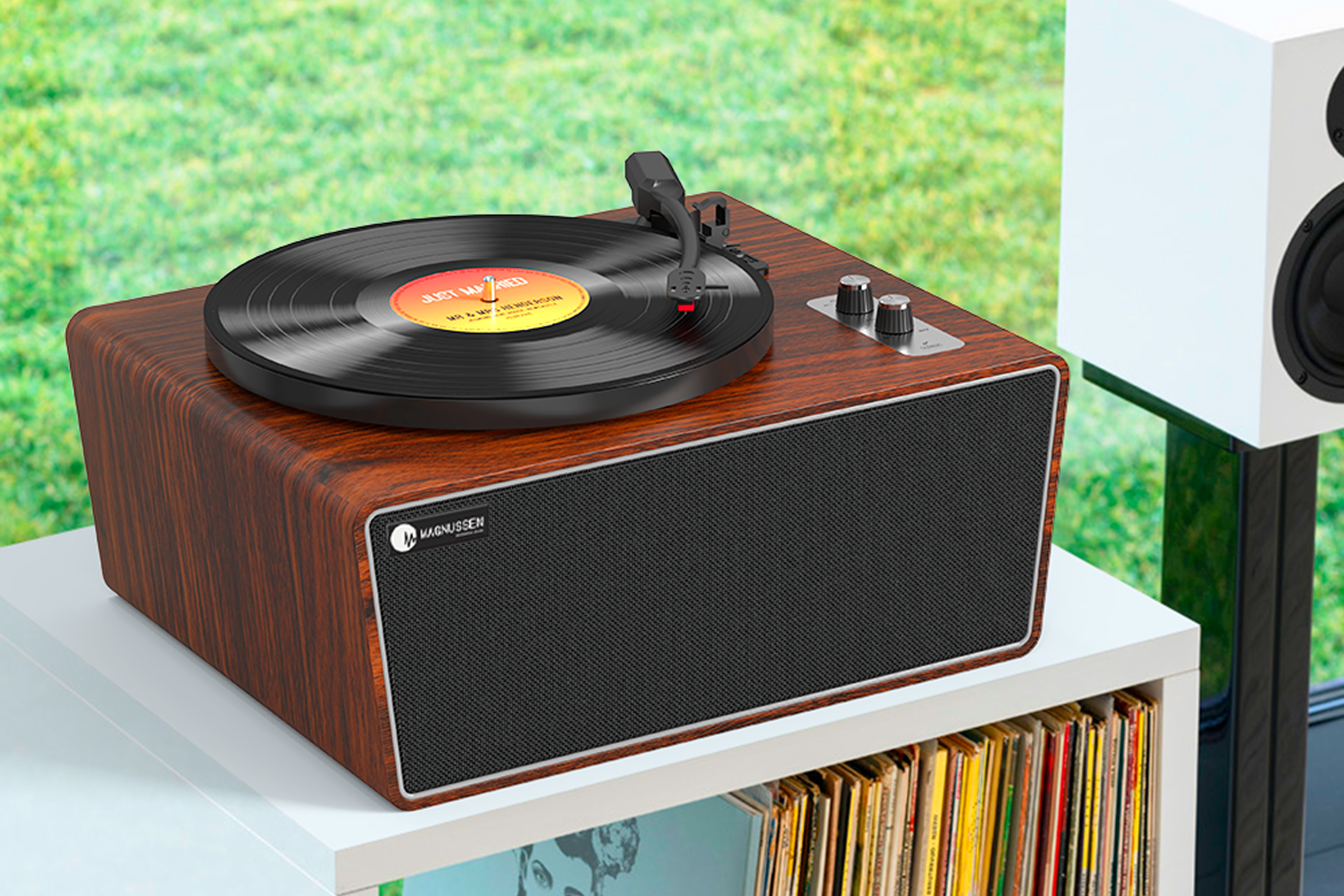 Un tocadiscos de madera con un disco encima. Un altavoz blanco al fondo.