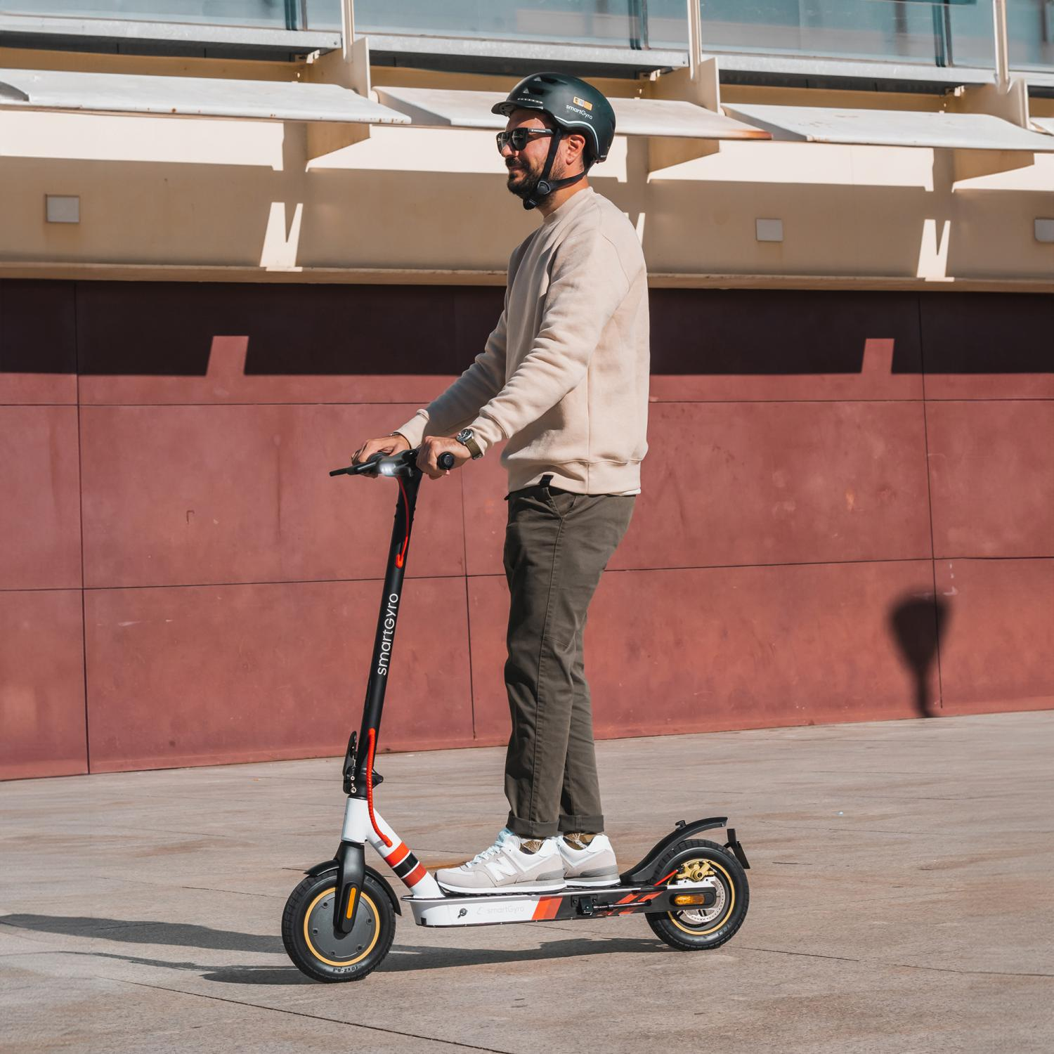 Un hombre con casco en patinete al aire libre en un día soleado.