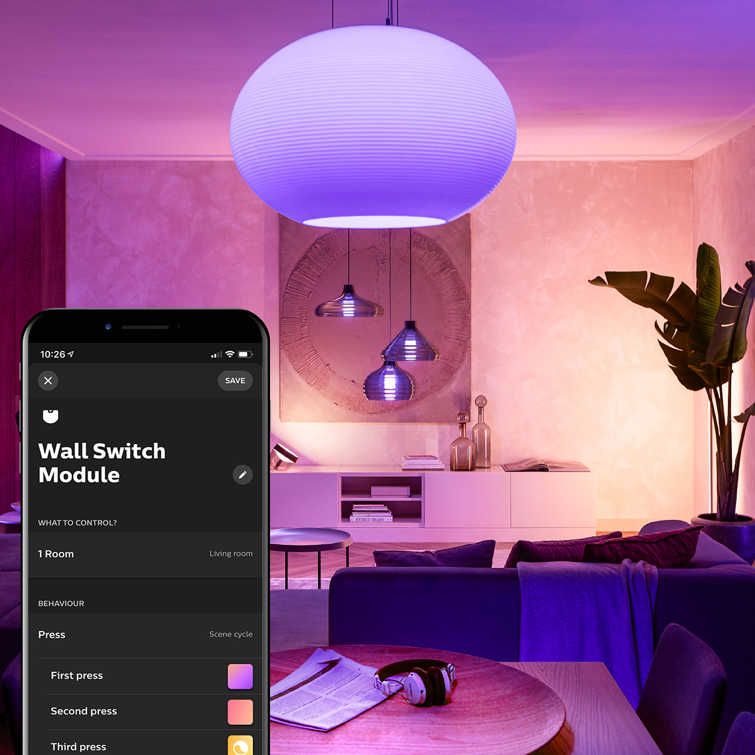 Eine große weiße Pendelleuchte befindet sich in einem Raum. Ein Telefon zeigt eine Smart-Home-App-Oberfläche.