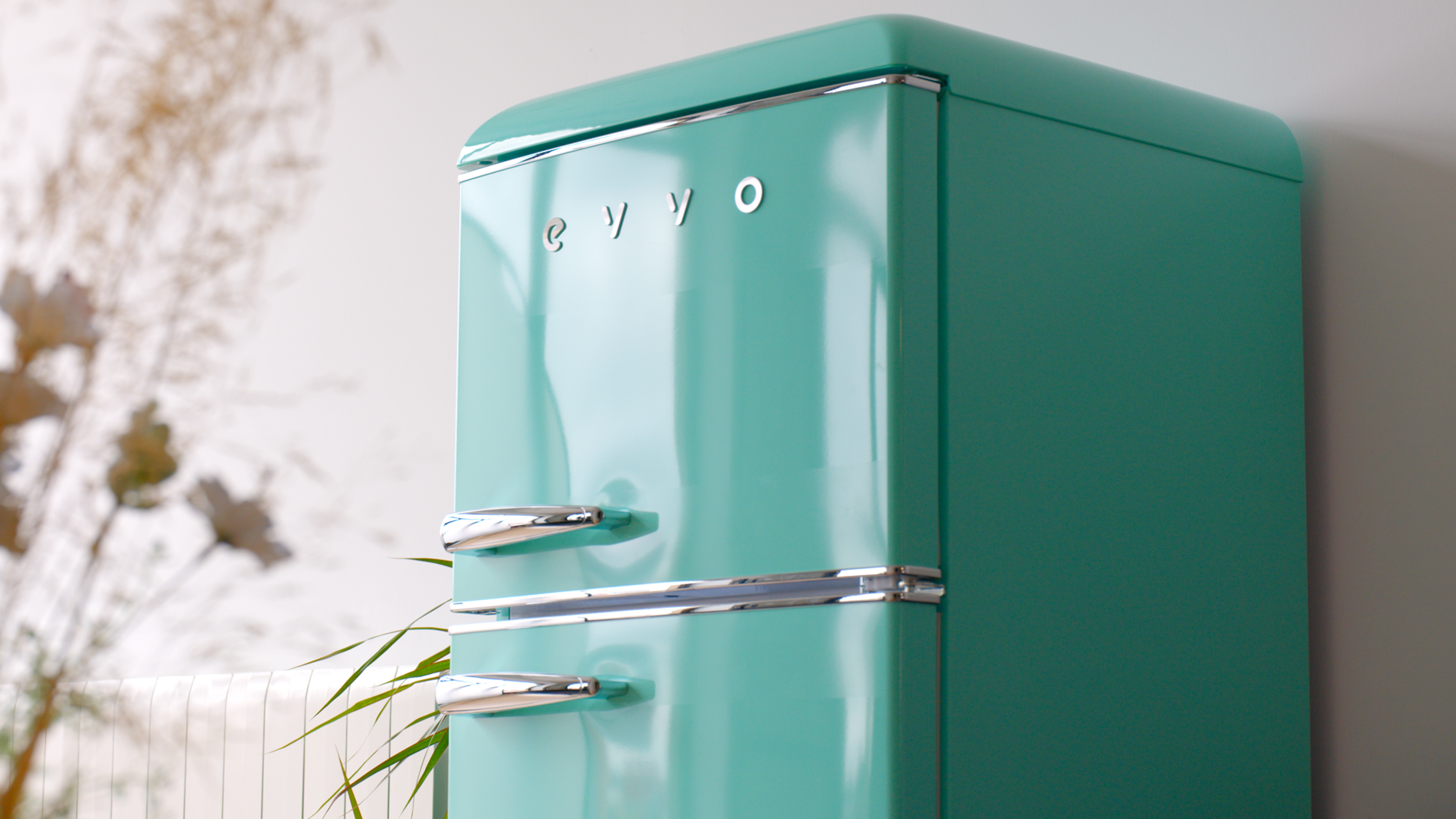 Un refrigerador retro color turquesa con detalles cromados, etiquetado con la palabra 'eyyo'.