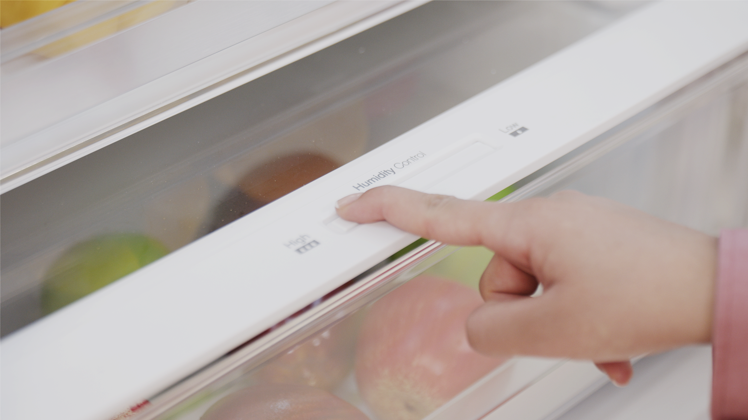 Una mano pulsa un botón que pone 'Humidity Control' en un cajón de nevera.