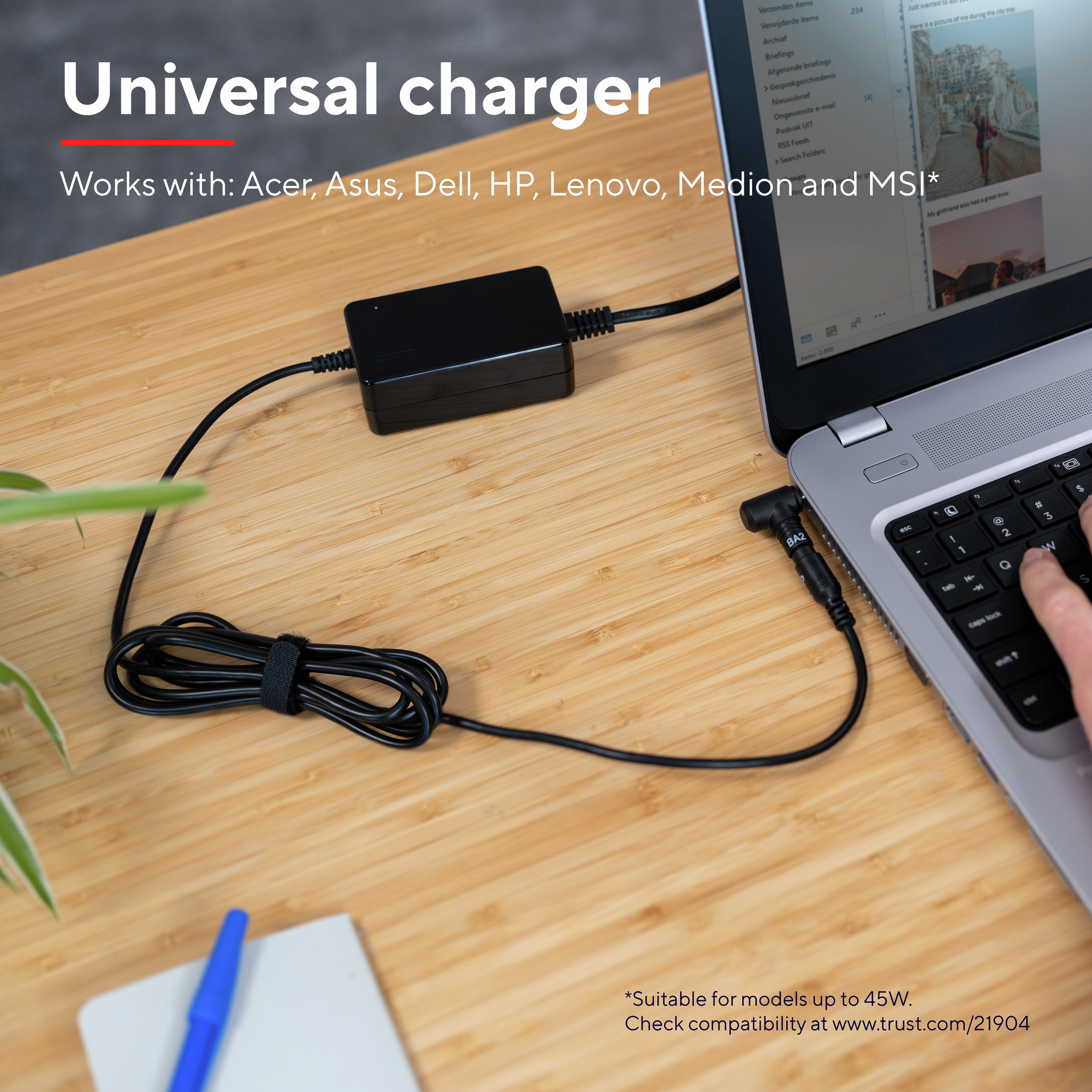 Chargeur universel connecté à un ordinateur portable. L'ordinateur portable est ouvert sur un bureau en bois.