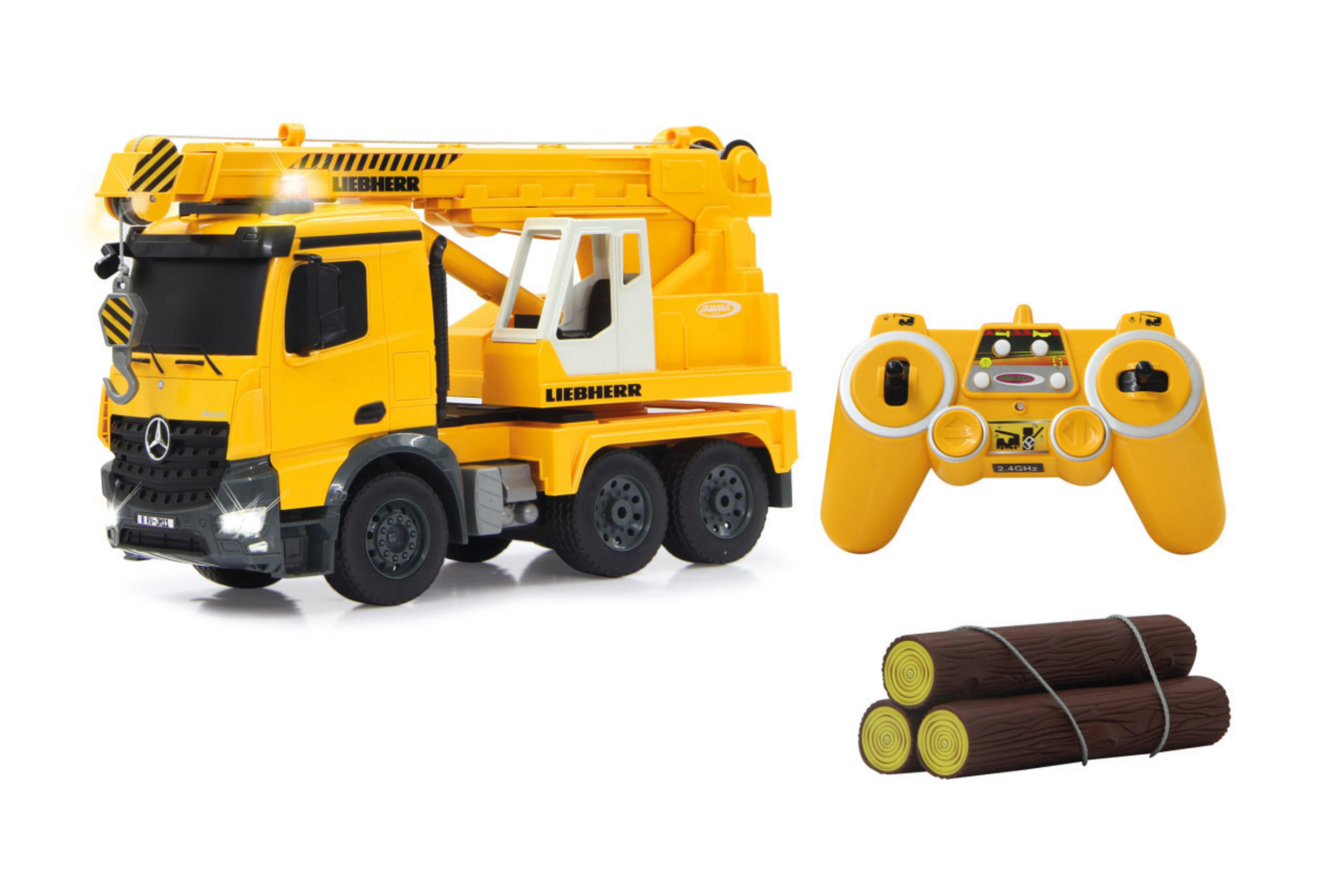 Gelber Spielzeugkranwagen, Fernbedienung und drei Holzstämme. Weißer Hintergrund.