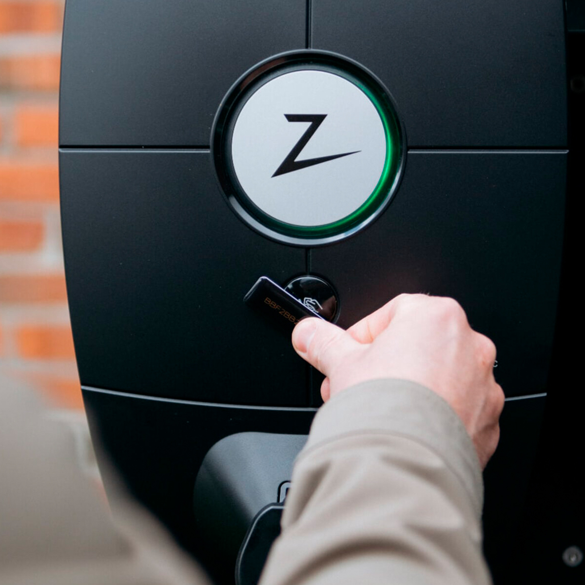 Hand with a key in front of an electric car charger.