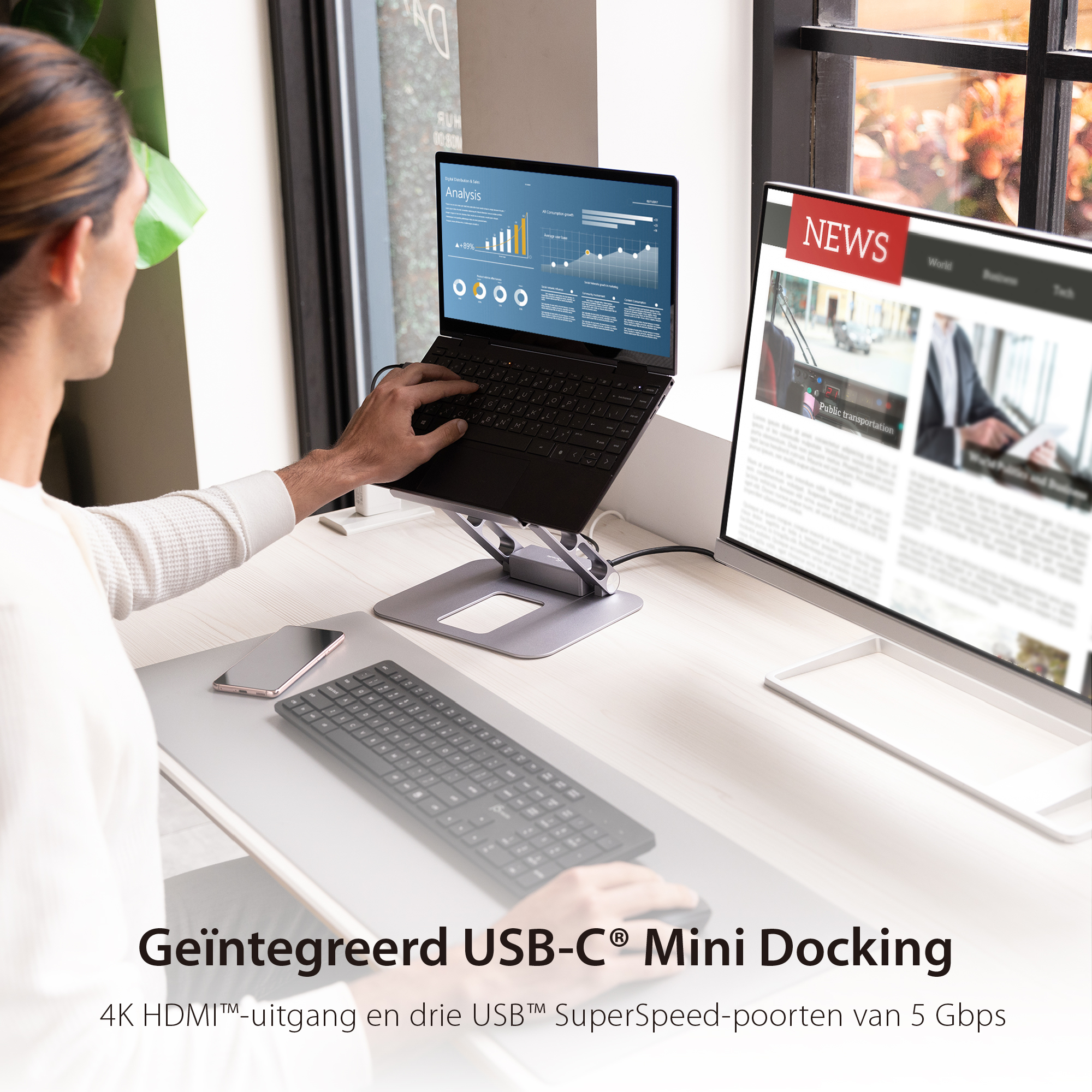 Ein Mann arbeitet an einem Schreibtisch mit Laptop und Monitor. Der Laptop steht auf einem Ständer.