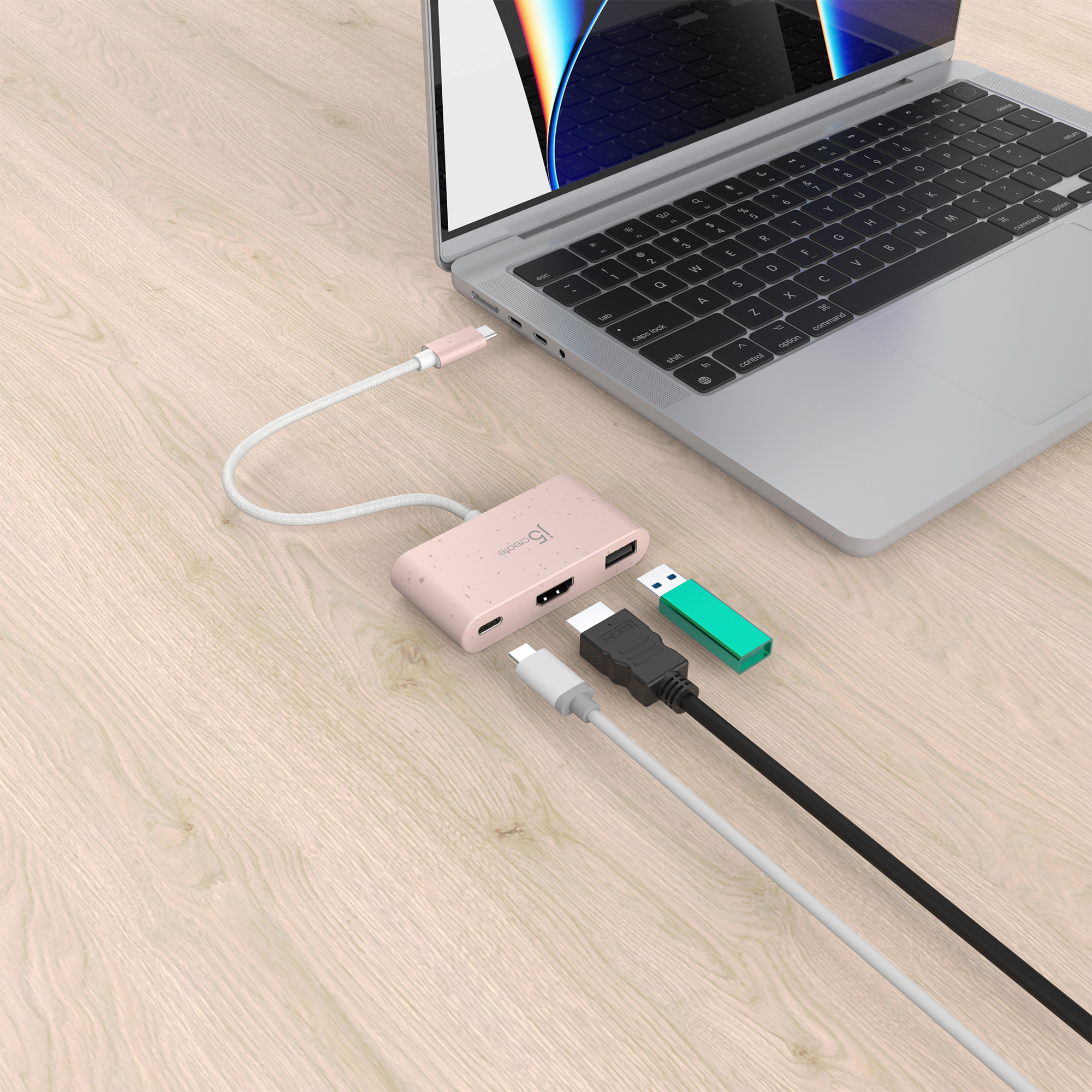 Ein Laptop mit einem pinkfarbenen Hub, der angeschlossen ist. Verschiedene Kabel wie HDMI und USB-Stick sind vorhanden.