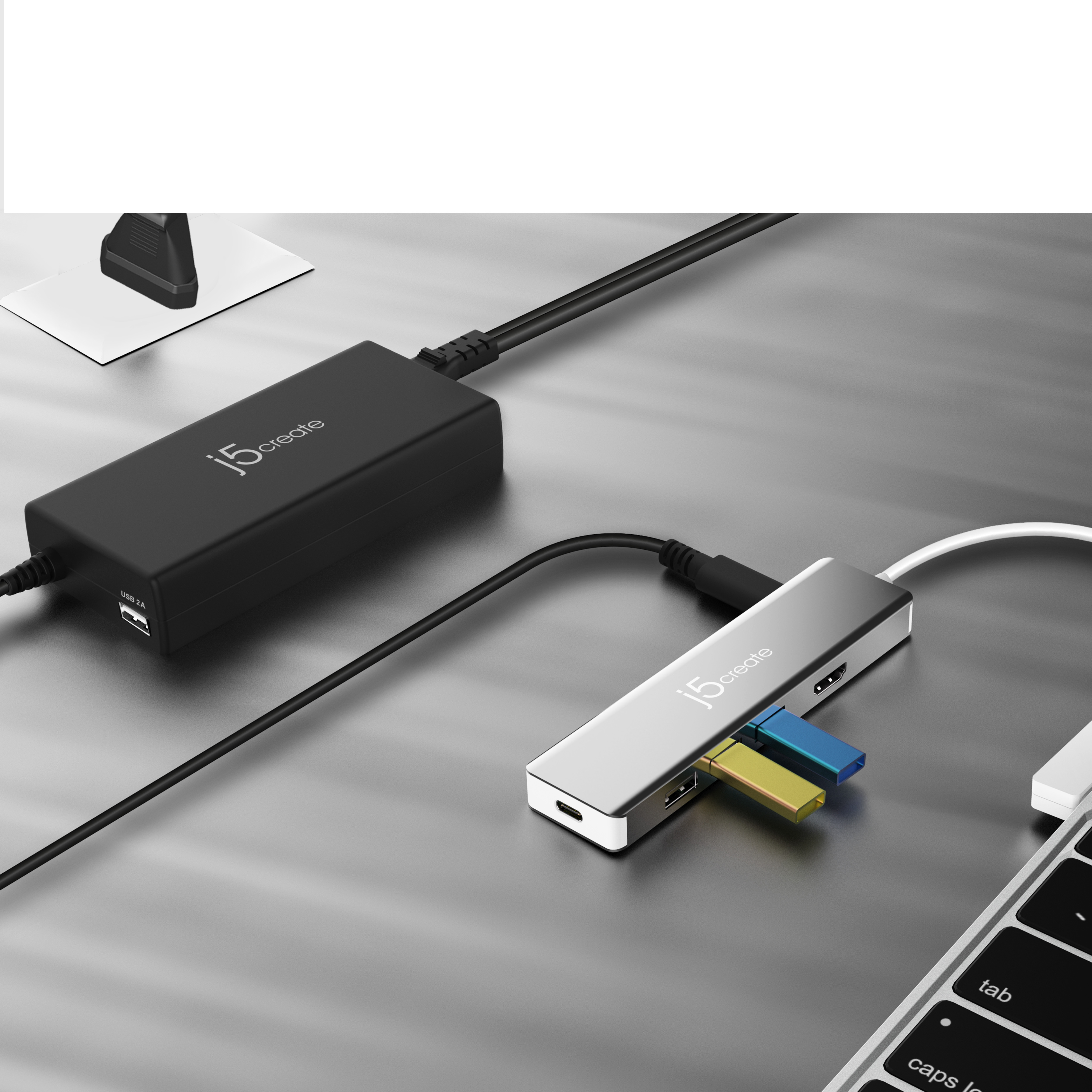 Adaptador de corriente negro con puerto USB y concentrador USB conectado a un portátil.